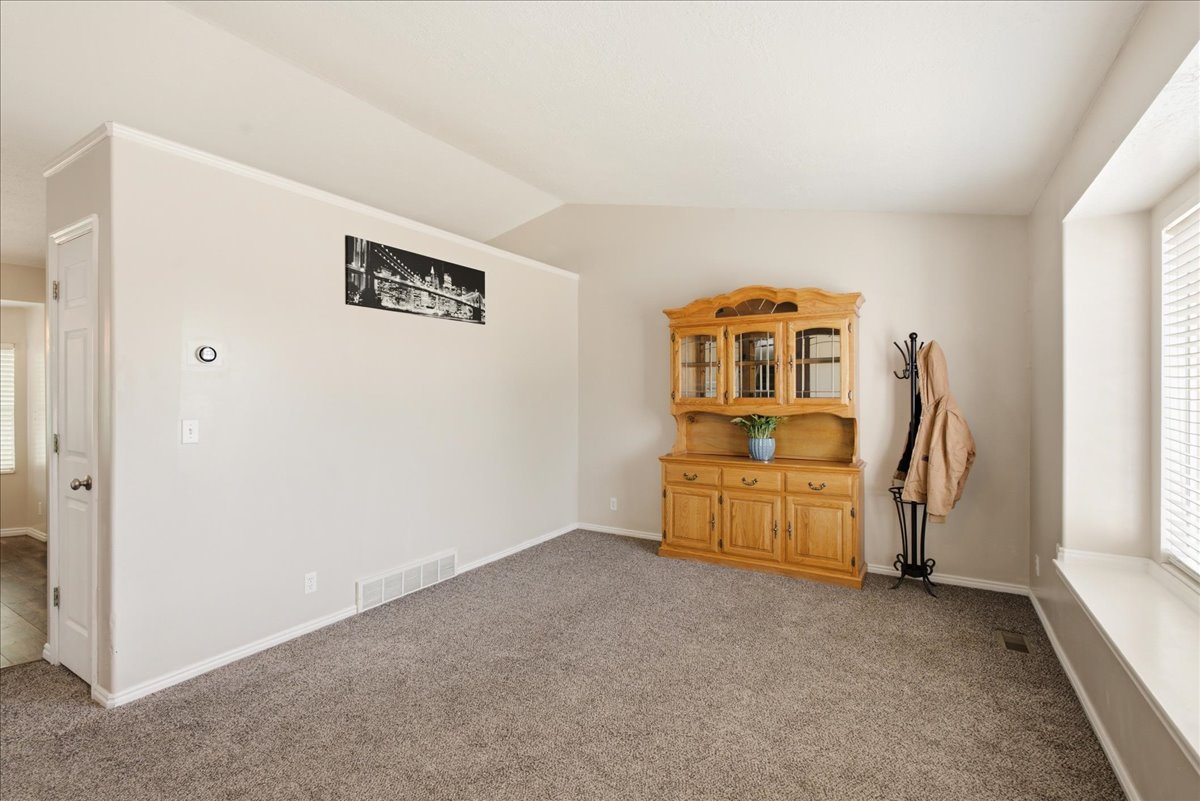 Spacious interior room with neutral-toned walls, gray carpeting, and white trim