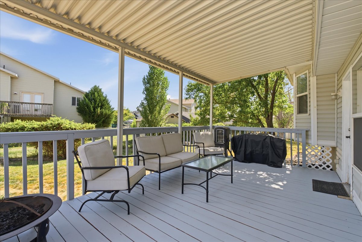Expansive covered deck featuring a light grey finish, white corrugated ceiling, and painted railings