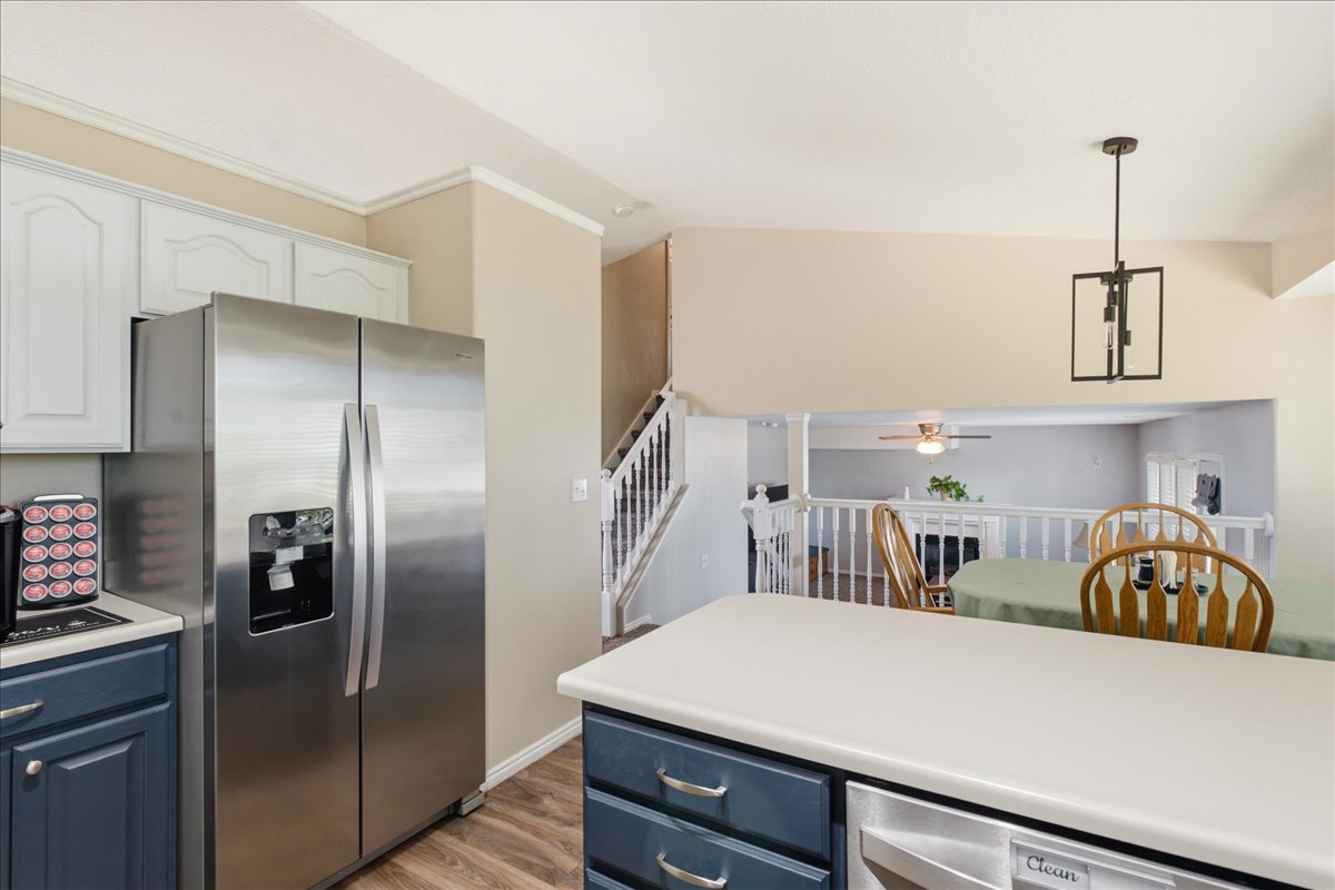 Kitchen with two-tone cabinetry, wood-finish flooring, and a stainless steel side-by-side refrigerator