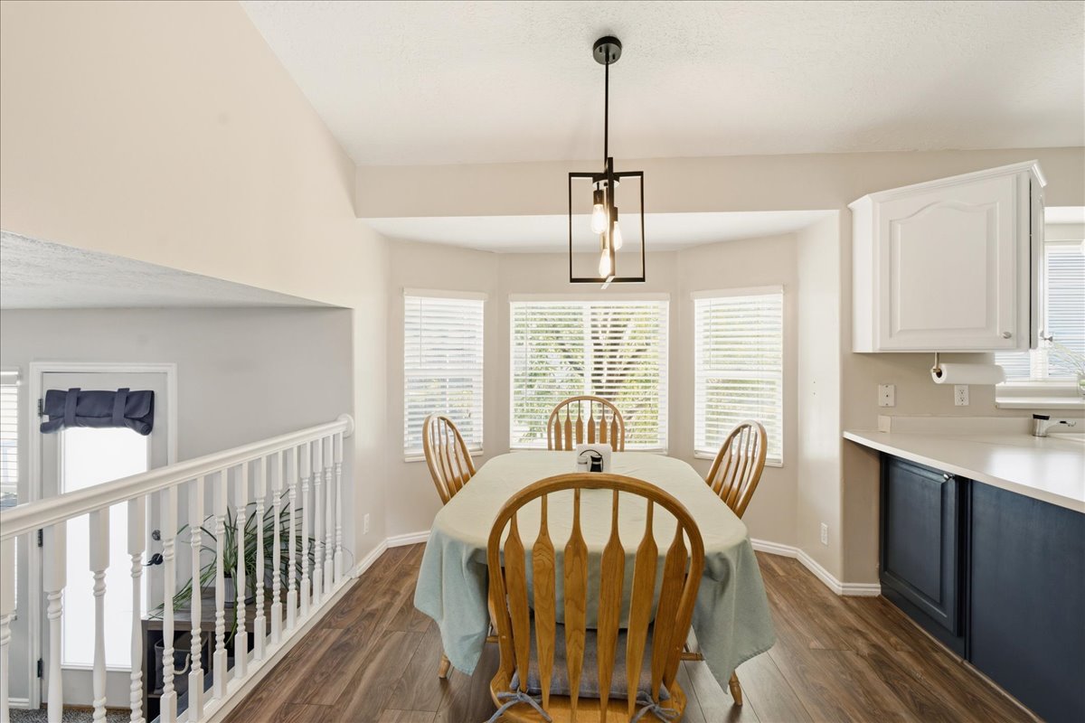 Dining area with wood-finish flooring, bay windows, and a contemporary linear chandelier