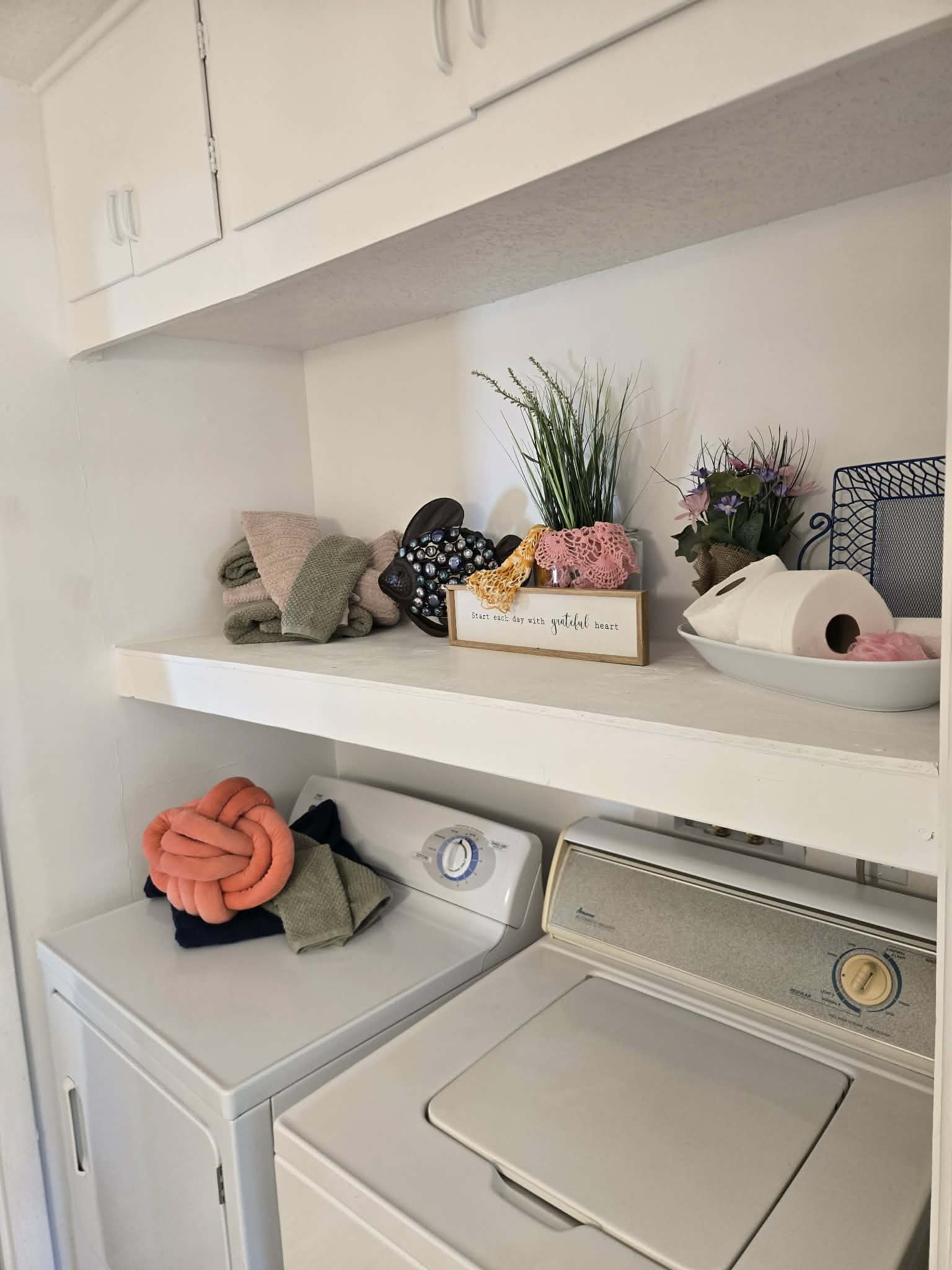 Laundry area with upper white cabinetry and open shelving