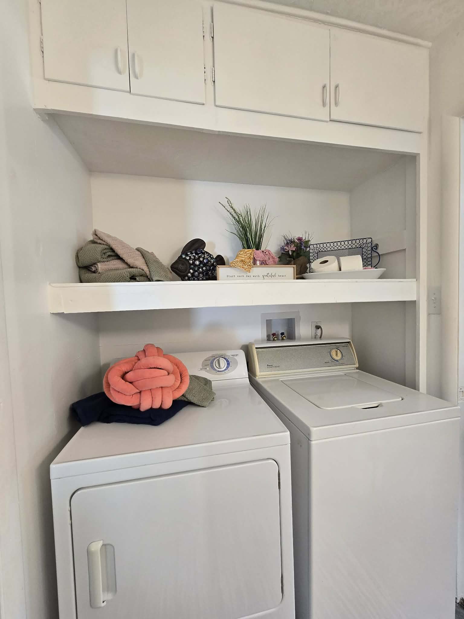 Dedicated laundry area featuring a built-in upper cabinet system and an integrated shelf for practical storage solutions