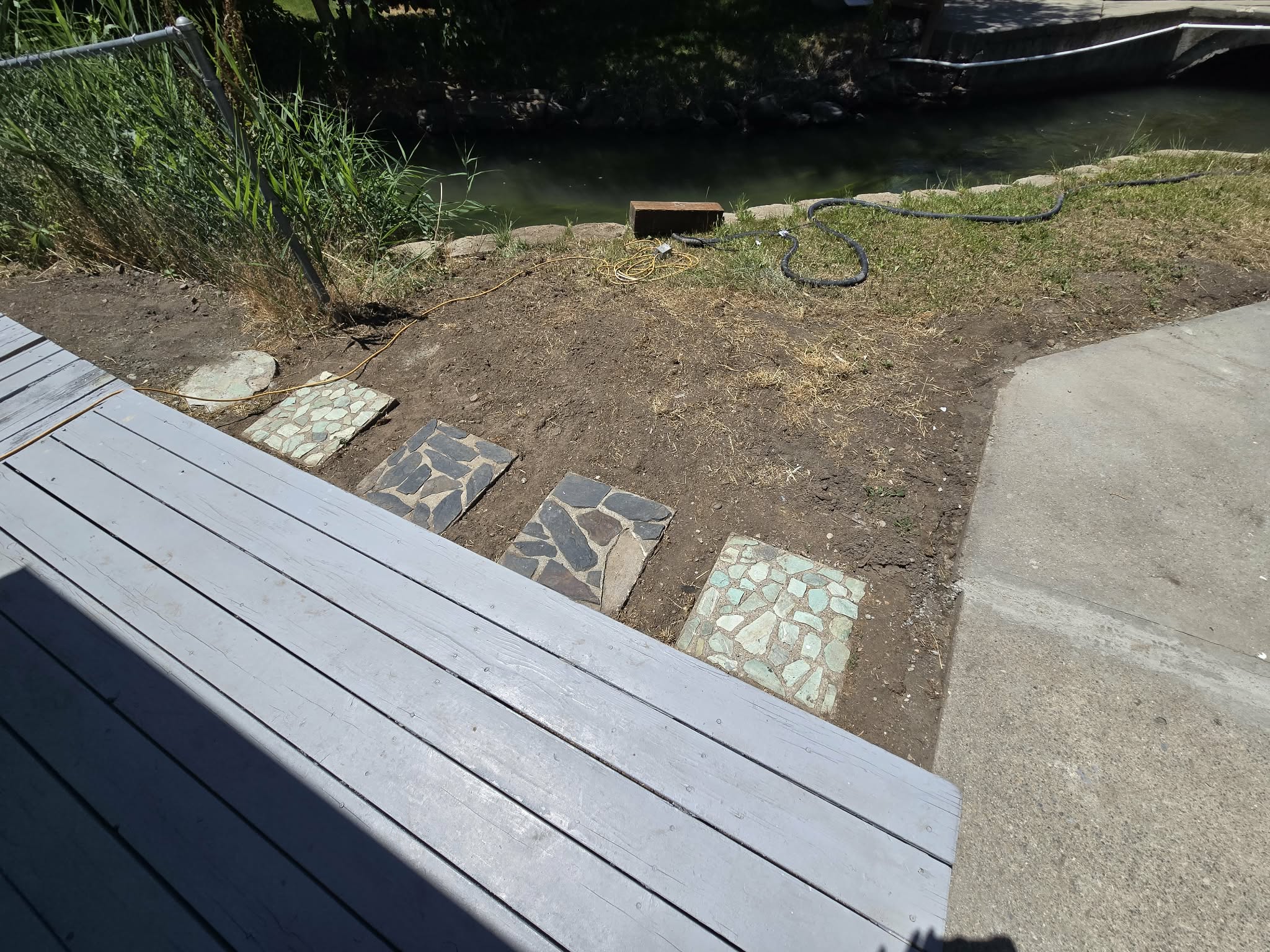 Wood-finish decking with stone pavers leading to a natural water feature