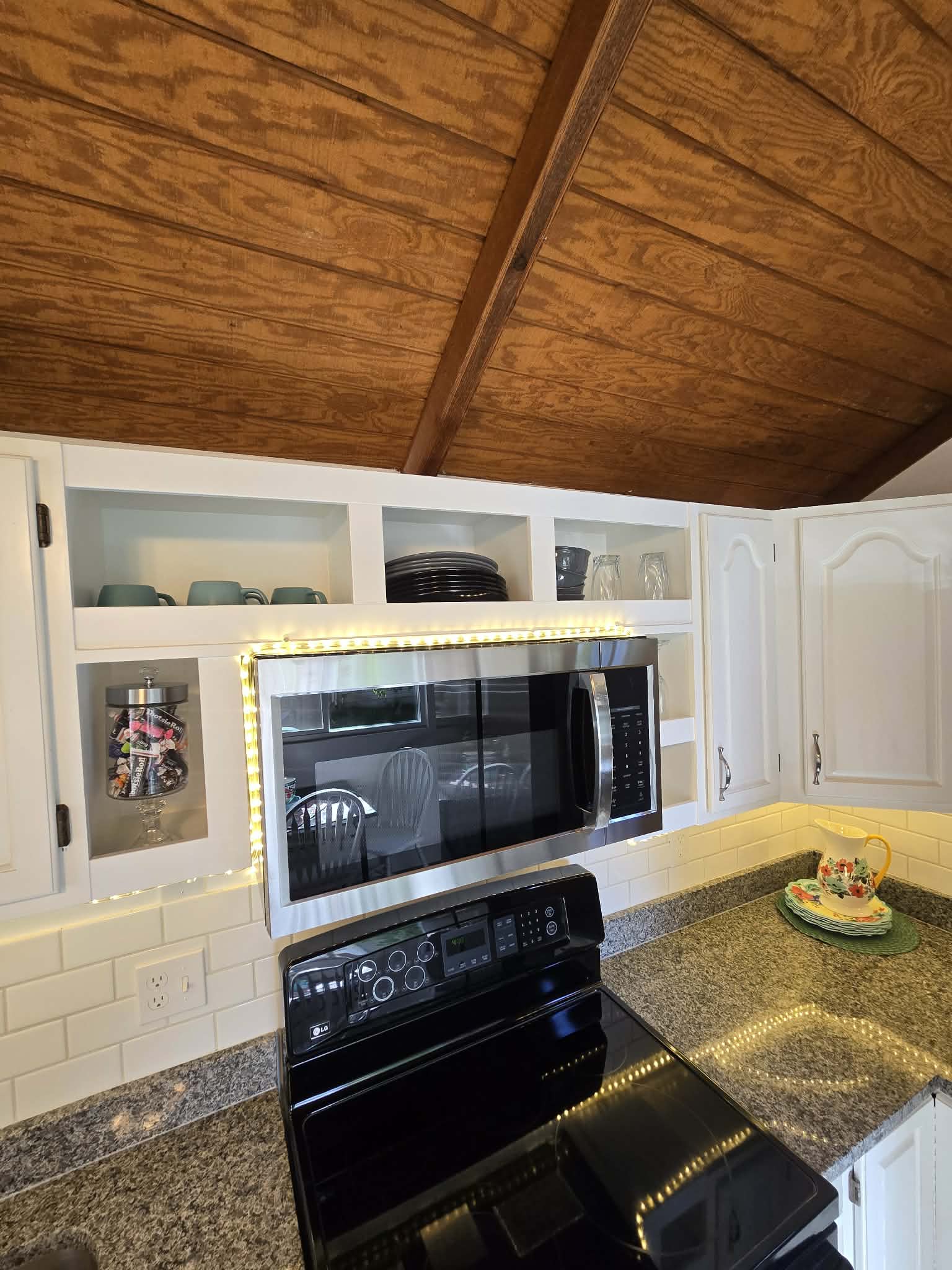 Kitchen featuring a wood-panel vaulted ceiling, white cabinetry, granite countertops, and a white subway tile backsplash