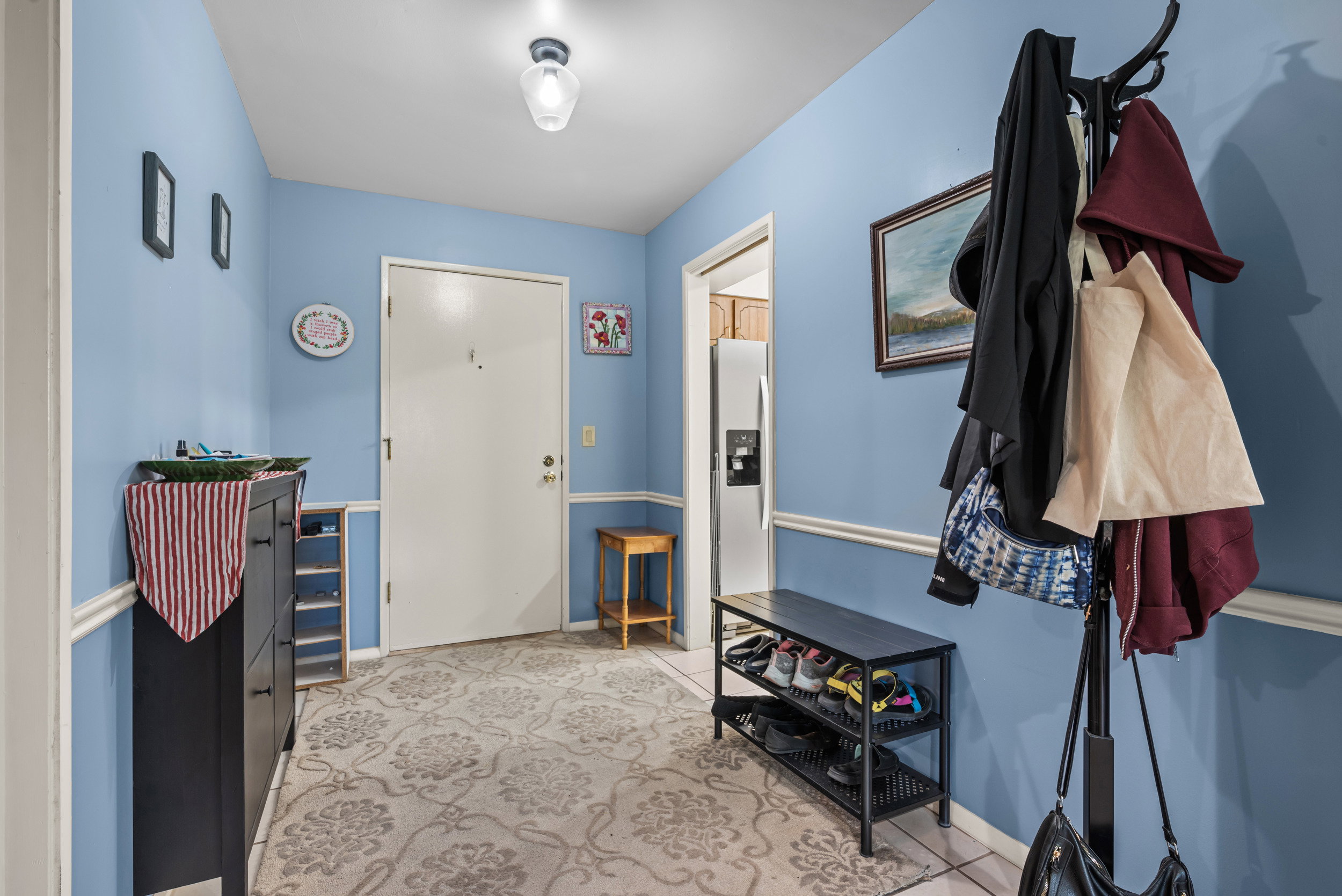 Entryway featuring a white door, blue walls with chair rail molding, and a decorative patterned area rug over tiled flooring