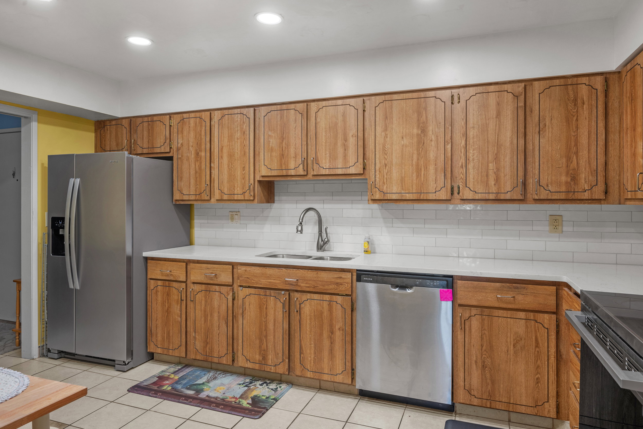 Kitchen featuring wood-finish cabinetry, white subway tile backsplash, and light-toned countertops