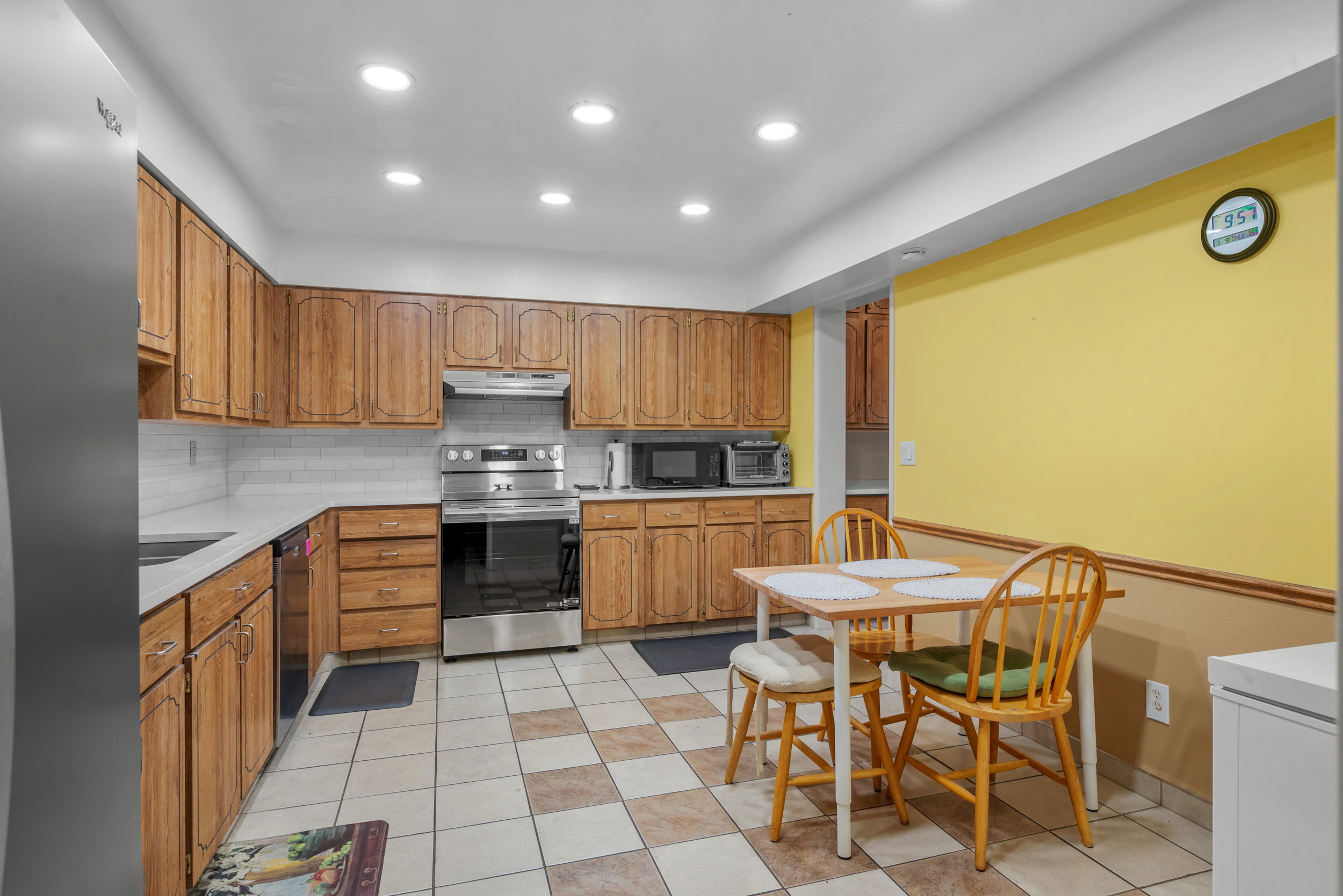 Kitchen featuring recessed lighting, extensive wood cabinetry, stainless steel appliances, a subway tile backsplash, and checkerboard tile flooring
