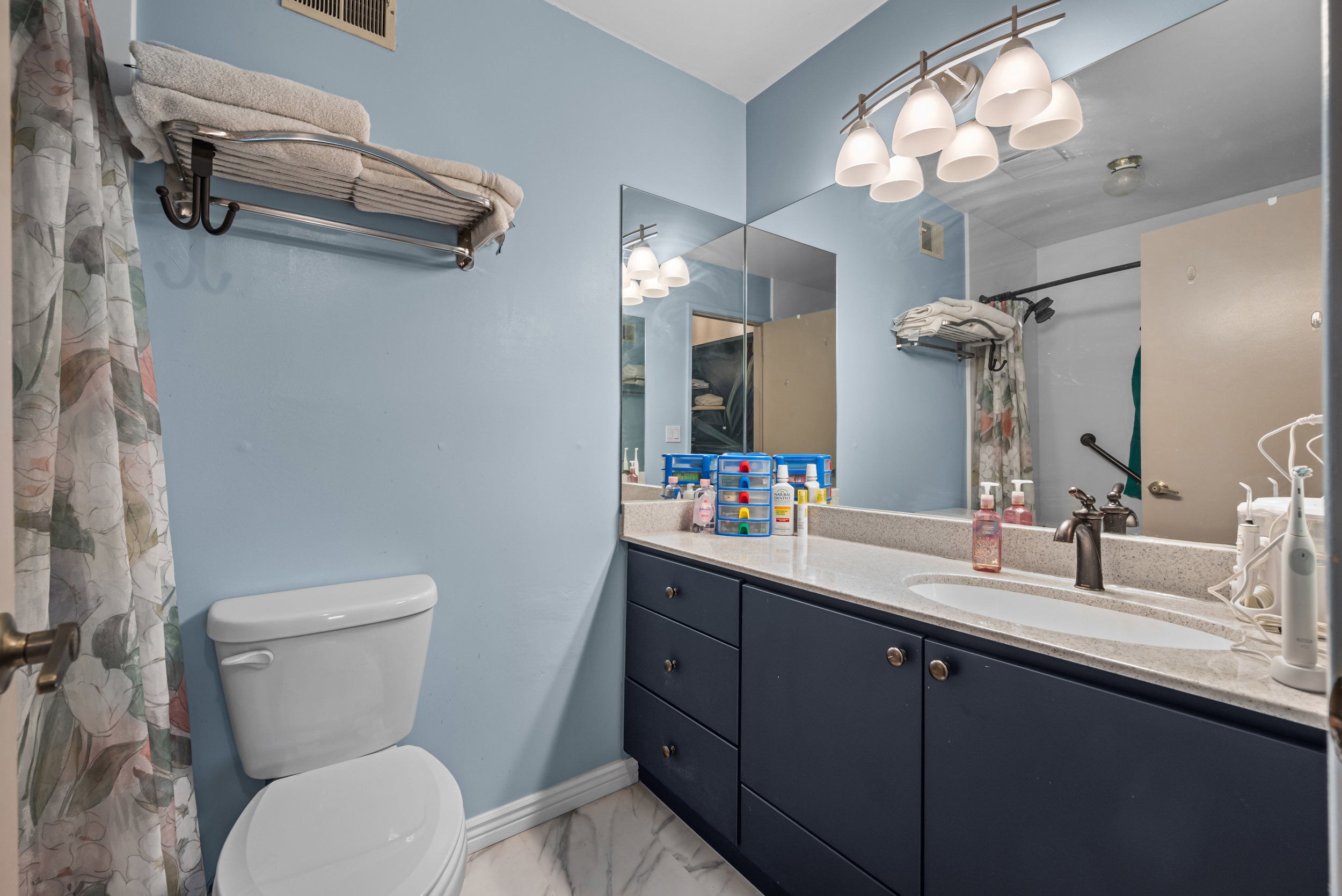 Bathroom featuring a single vanity with dark cabinetry, integrated sink, and light-toned countertop
