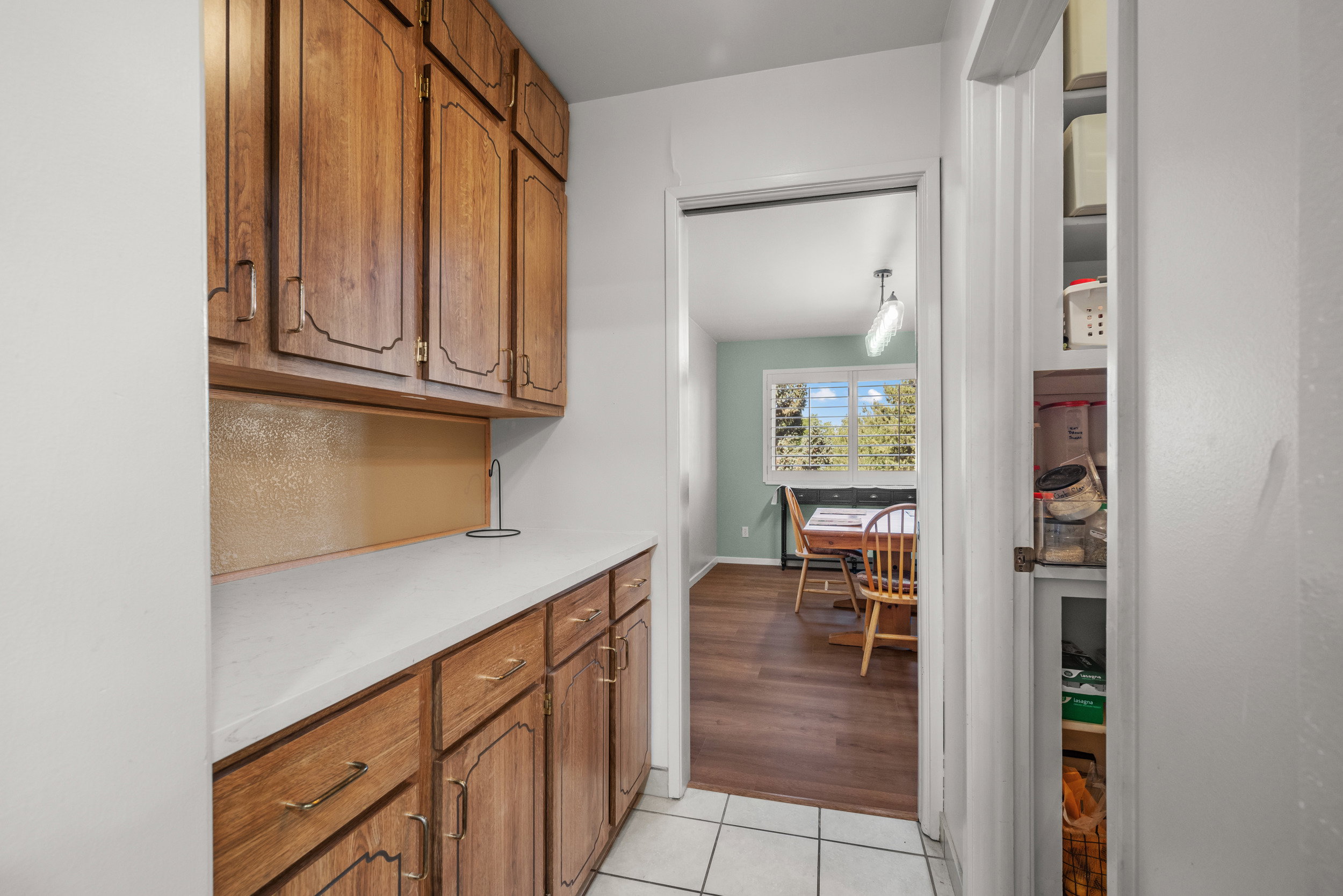 Kitchen galley with wood-finish cabinetry, light-toned countertops, and tile flooring