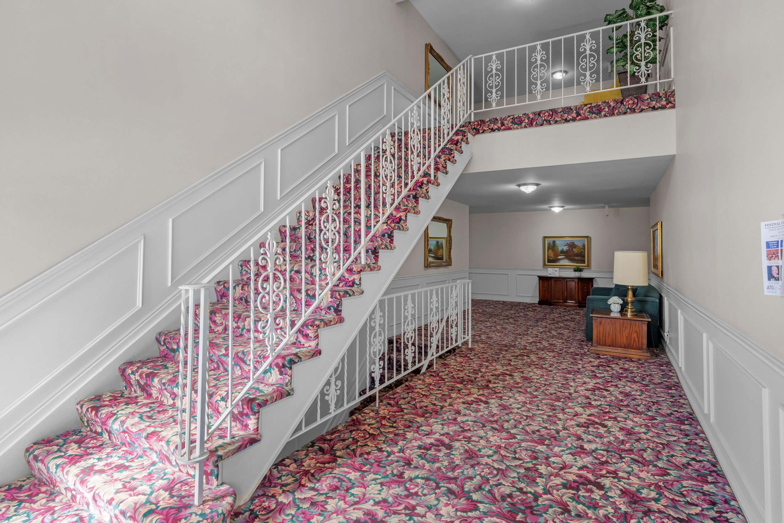 Staircase with ornate white railings and patterned carpet