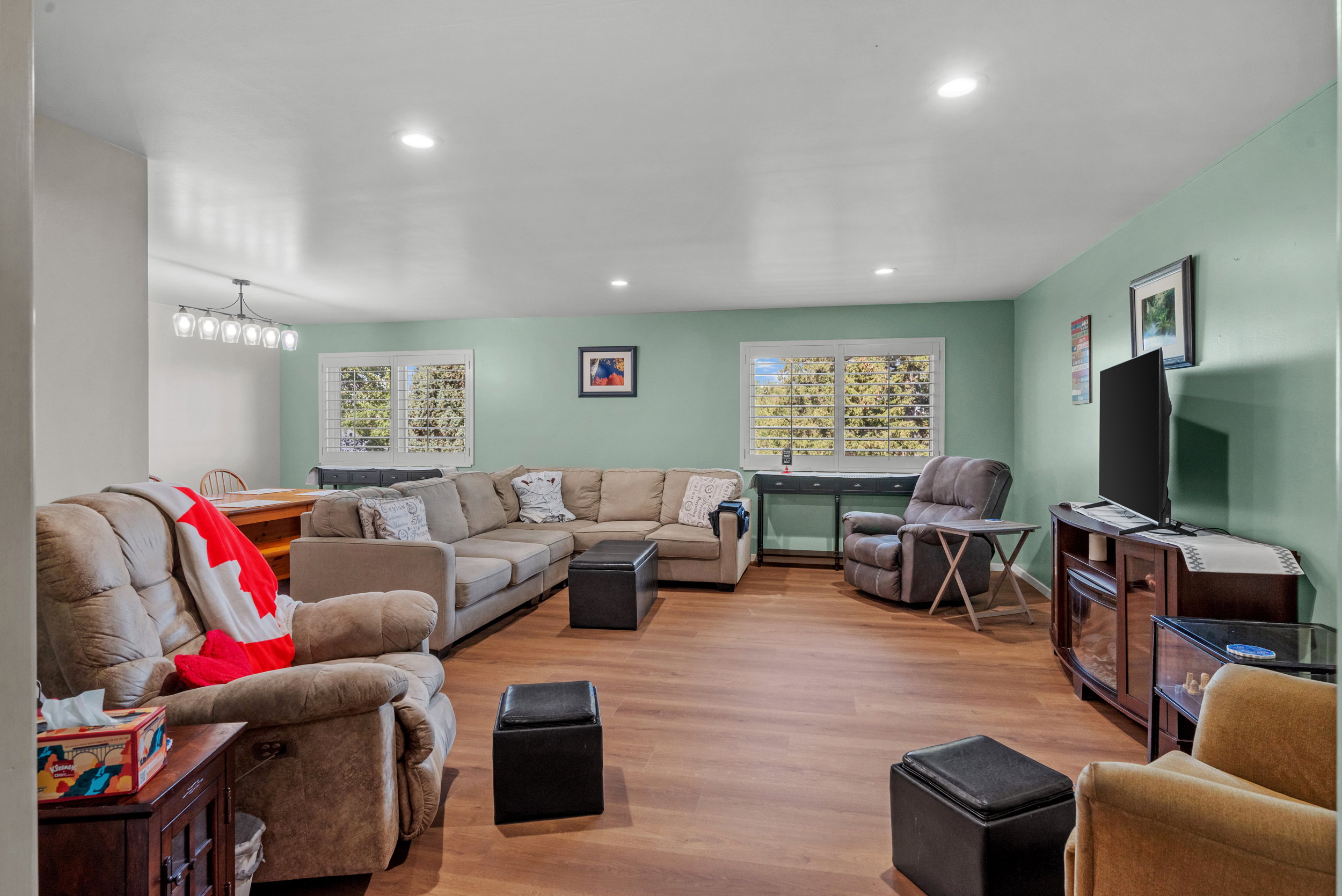 Spacious living area featuring wood-finish flooring, recessed lighting, and a soft green wall color