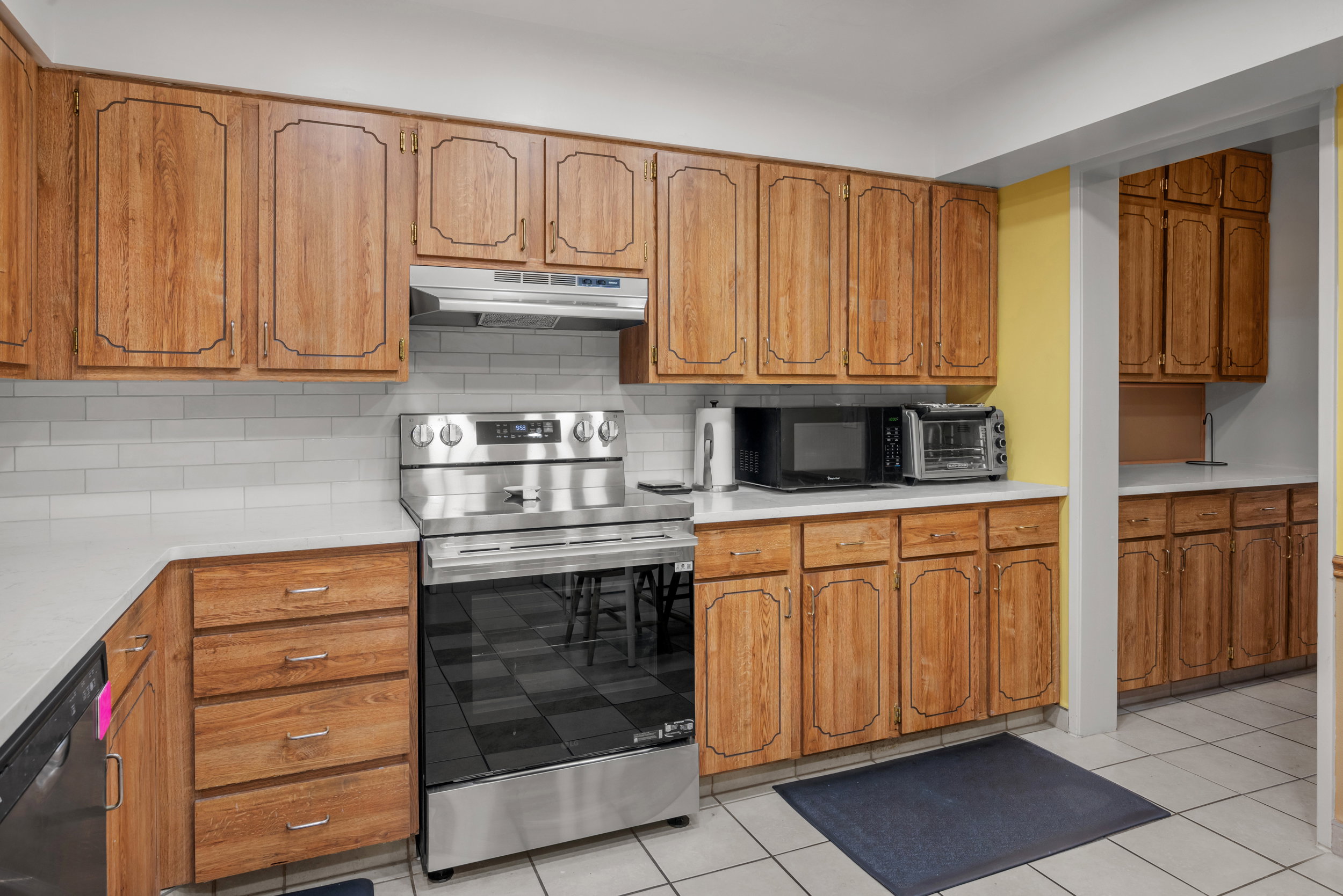 Kitchen featuring wood-finish cabinetry, white countertops, subway tile backsplash, and stainless steel range
