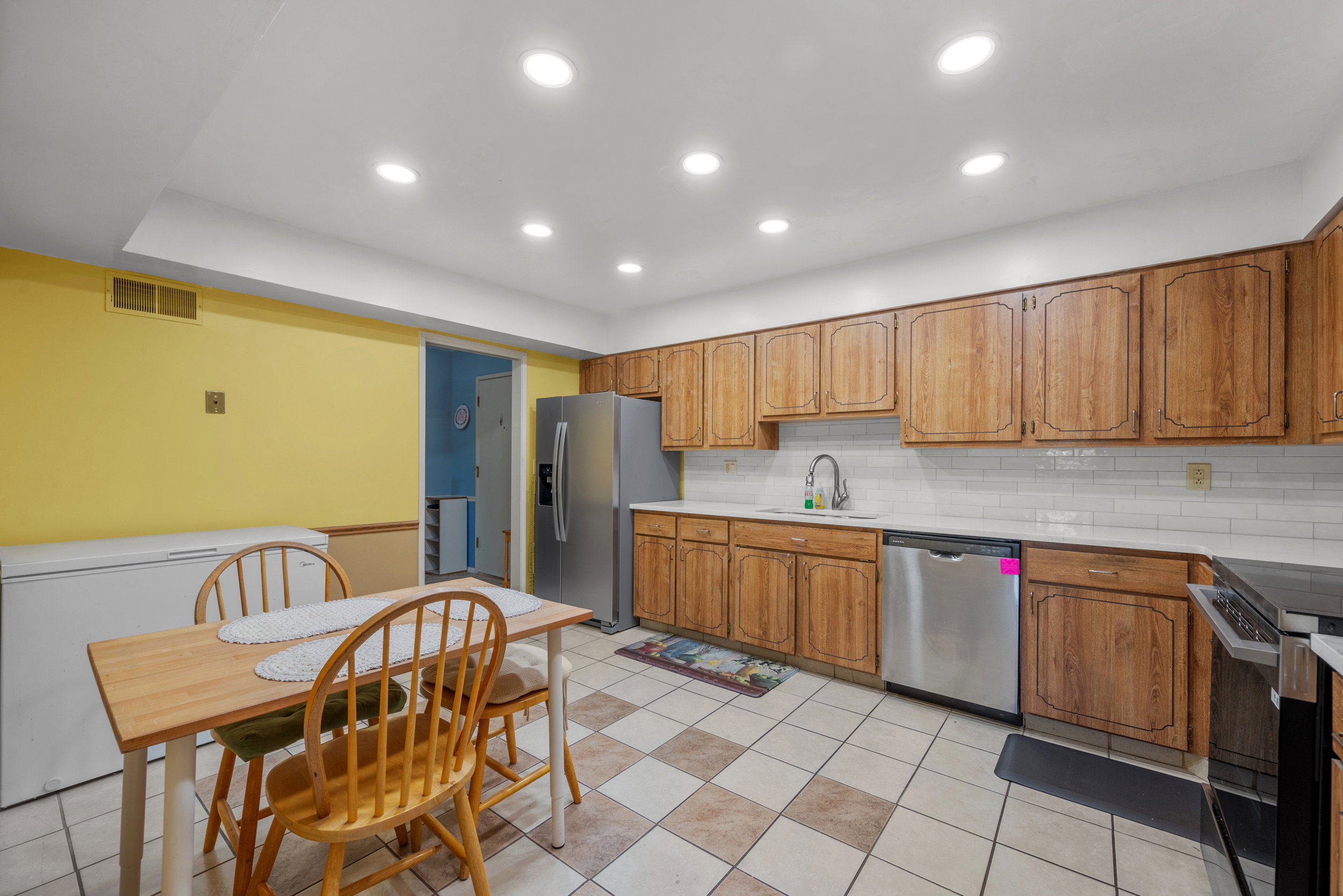 Functional kitchen featuring wood-finish cabinetry, white subway tile backsplash, and stainless steel appliances