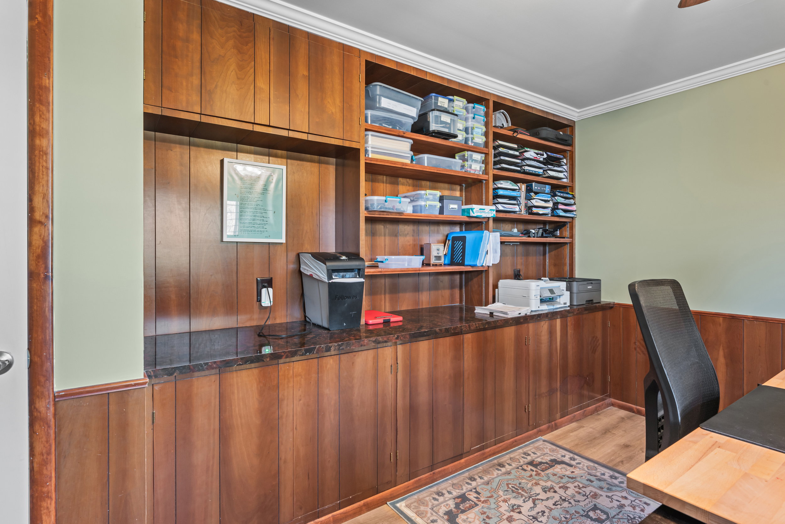 Built-in wood-finish shelving and paneling with a stone-finish countertop
