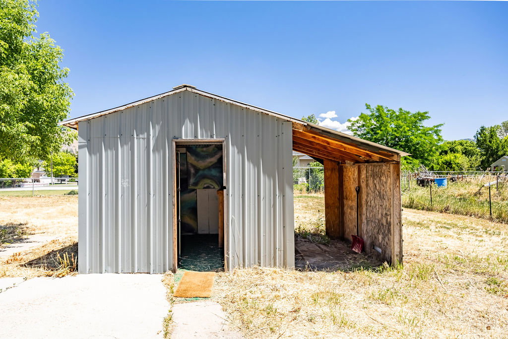 Metal utility shed with an attached covered lean-to. Within the shed, there's a cool bomb shelter access, or it could just be an awesome root cellar.