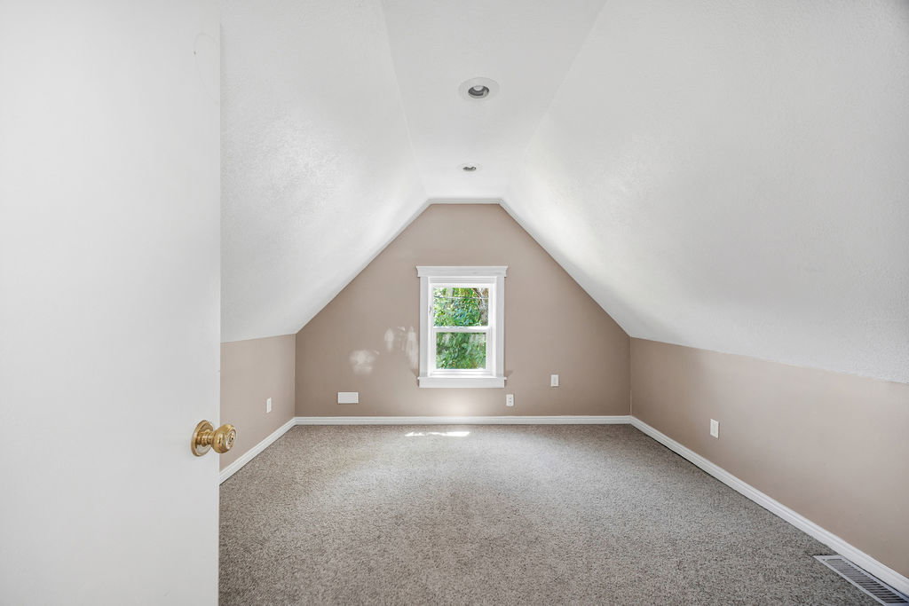 Bedroom featuring sloped ceilings, recessed lighting, and a single window with white trim