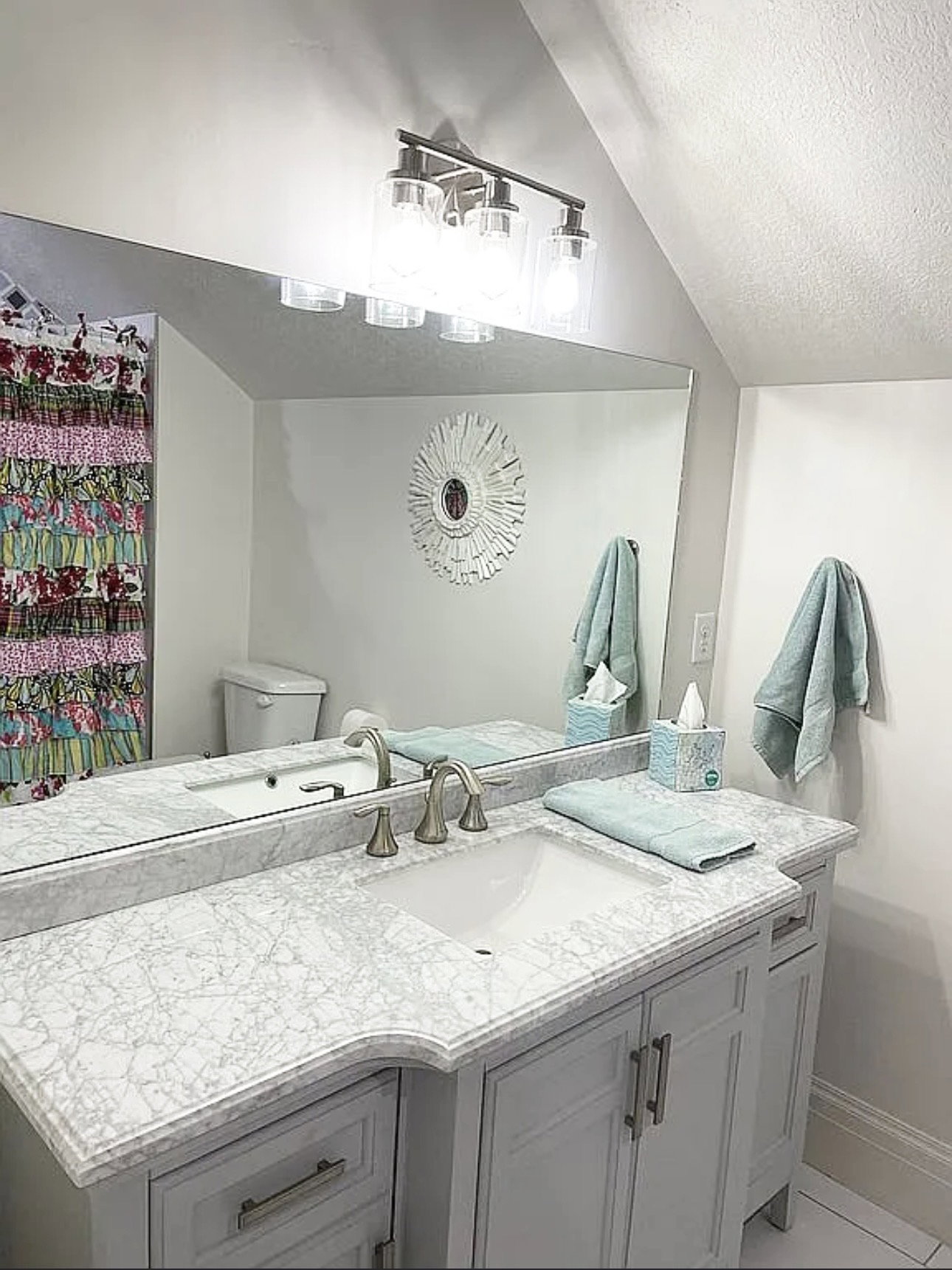 Vanity with undermount sink, intricate patterned countertop, and light gray cabinetry