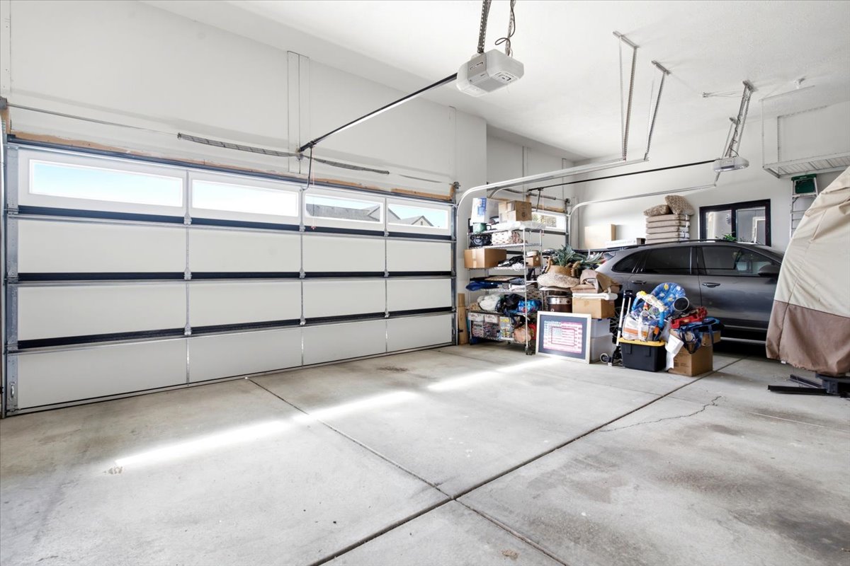 Two-car garage featuring a sectional garage door with upper window inserts, concrete flooring, and an automatic garage door opener