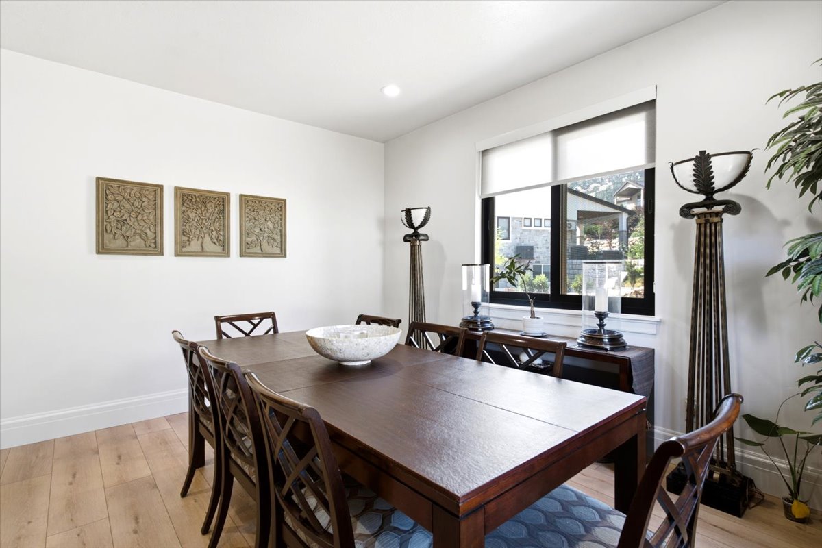 Spacious dining area featuring light wood-finish flooring, white baseboards, and bright white walls