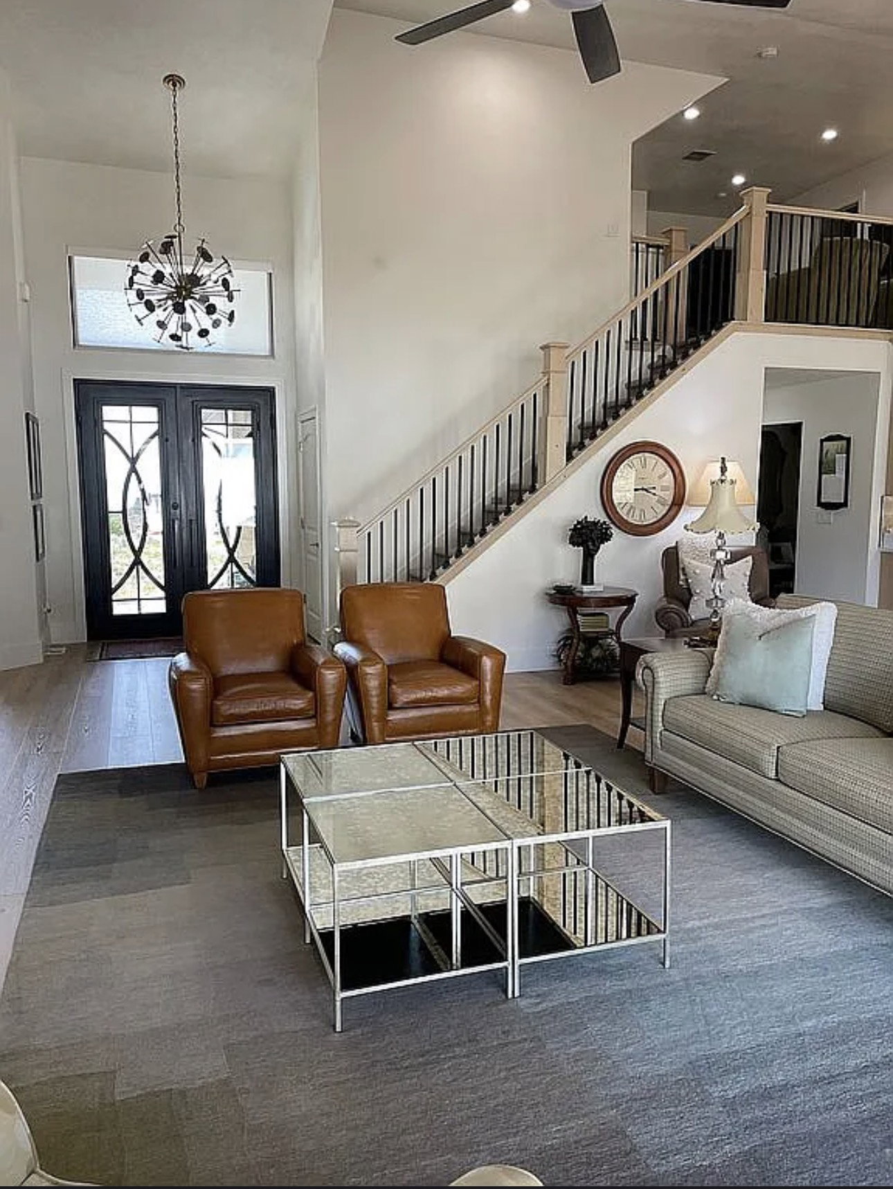 Two-story living area featuring a prominent staircase with black wrought iron spindles and light wood newel posts