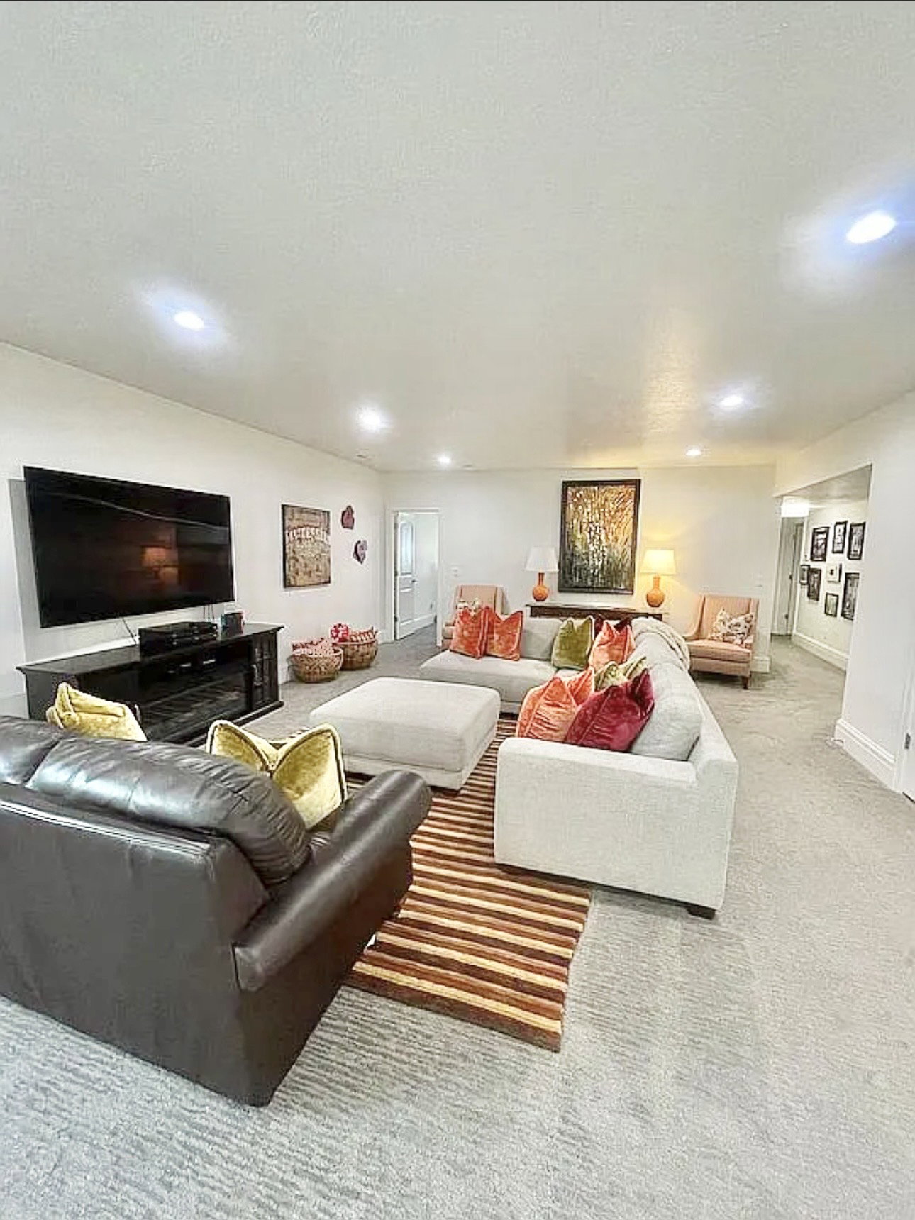 Spacious entertainment area featuring recessed lighting, light-colored walls, and a large flat-screen television