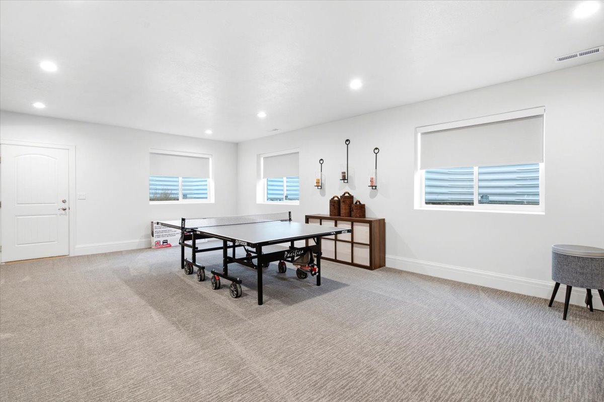 Spacious room featuring neutral carpeting, recessed lighting, and multiple windows with roller shades