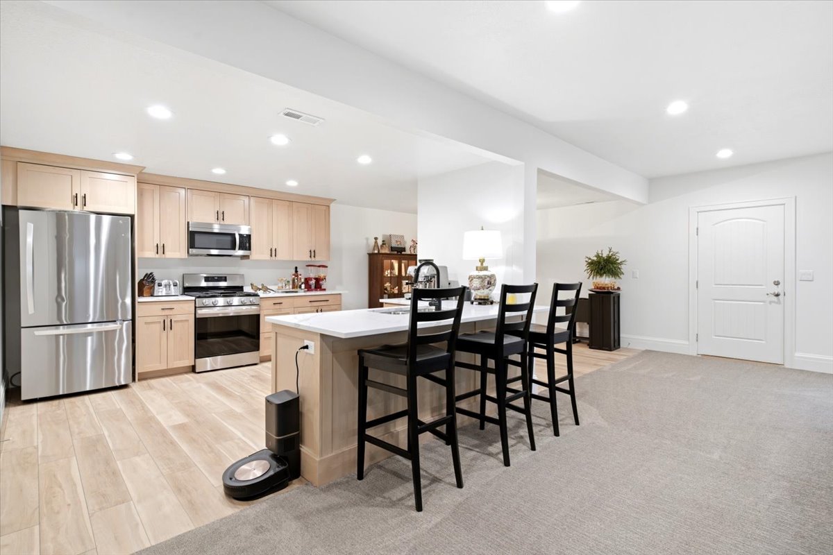 Open-concept kitchen with light wood-finish cabinetry, stainless steel appliances, and a central island with bar seating