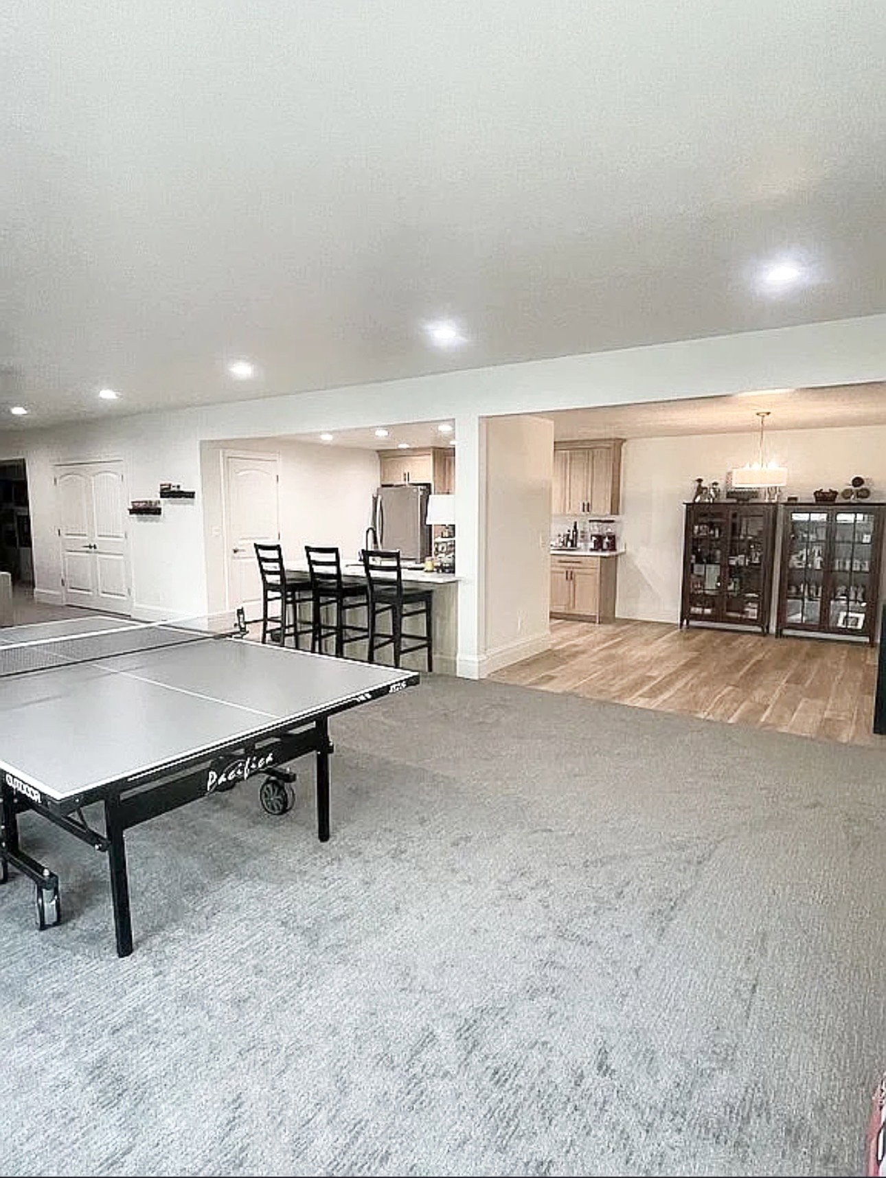 Spacious open-concept area featuring recessed lighting, light-toned carpeting, and a separate room with wood-finish flooring
