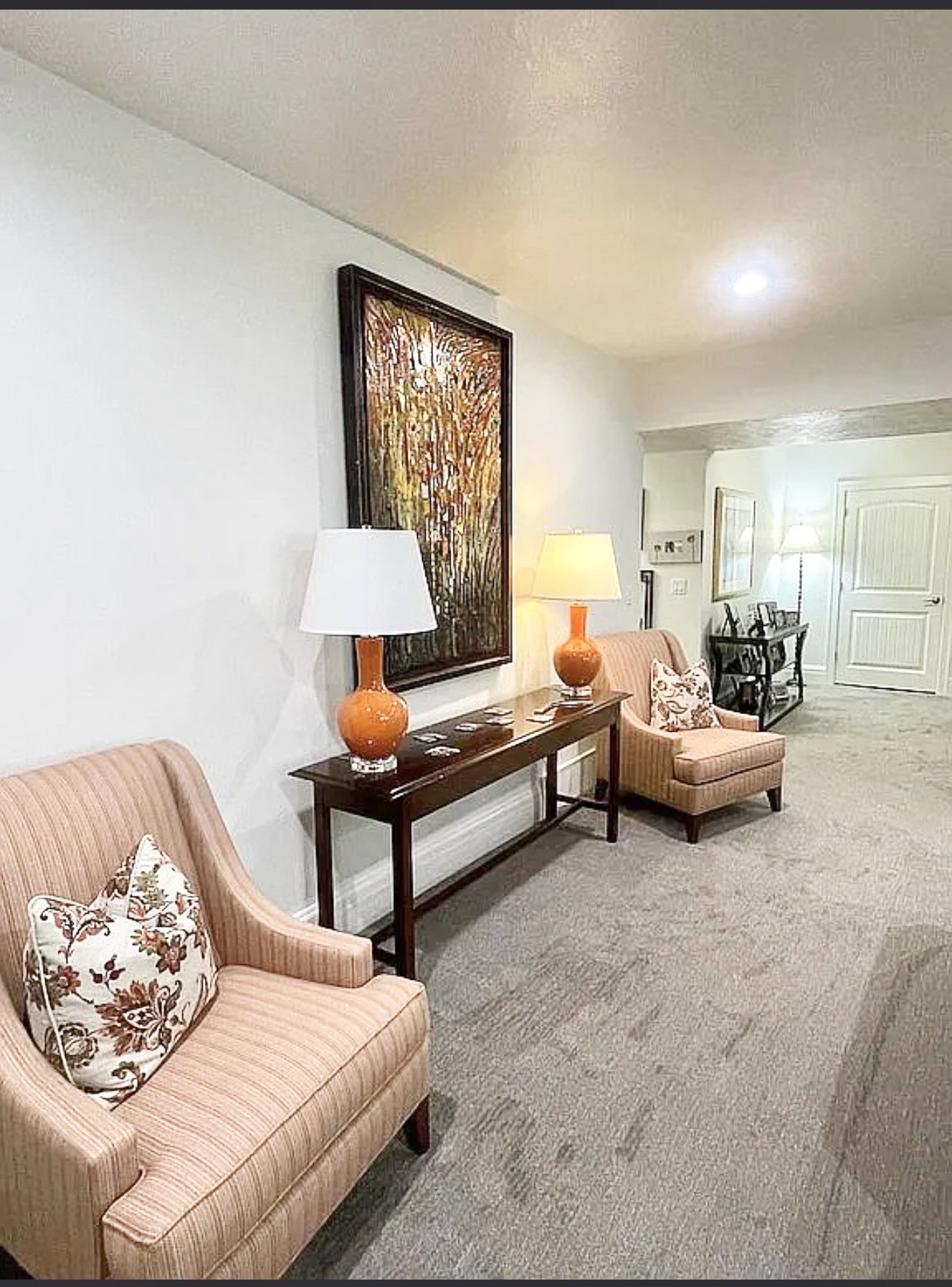 Recessed lighting illuminates a space featuring light-toned walls and patterned carpeting