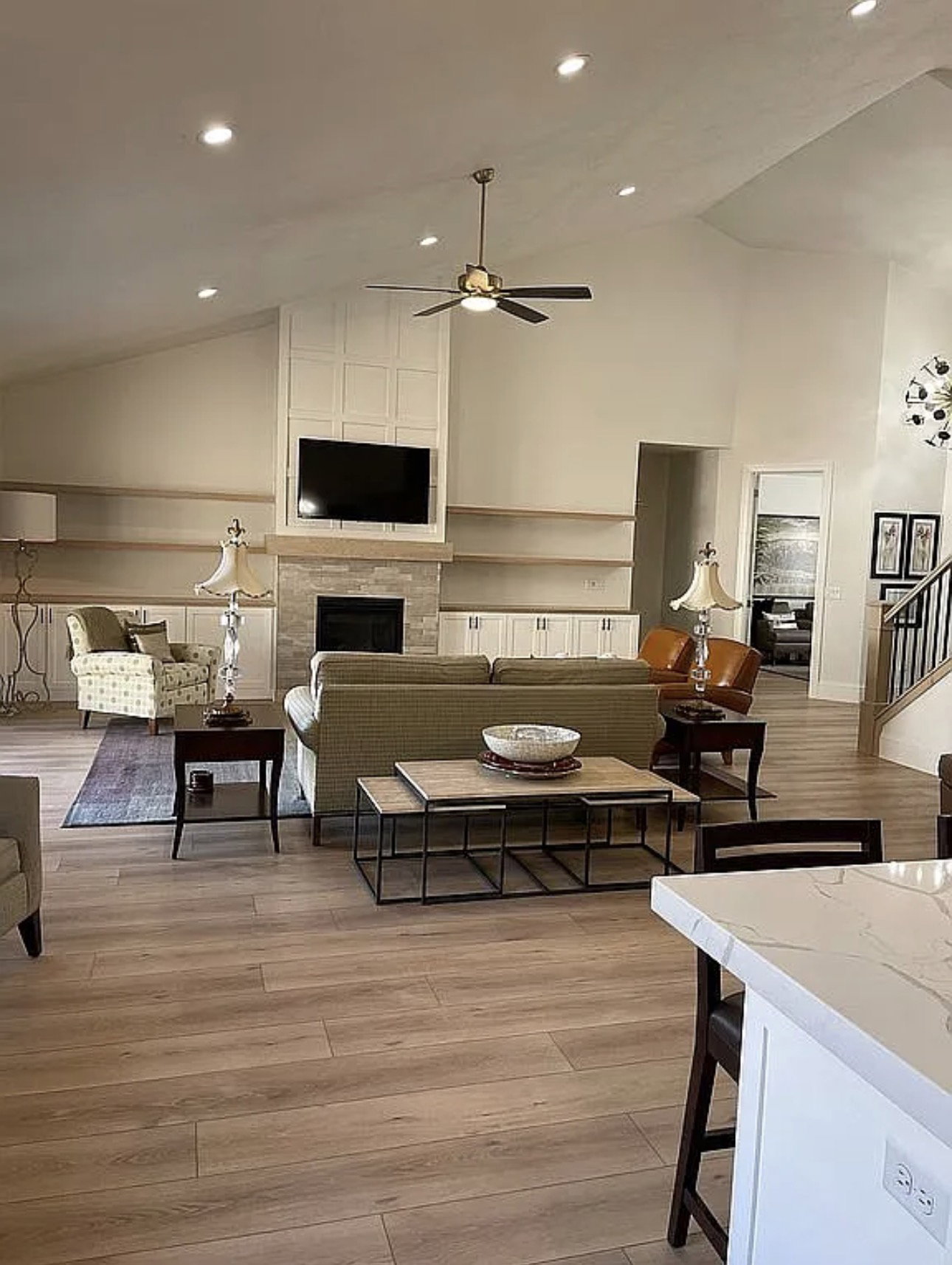 Spacious living area featuring wood-finish flooring, a vaulted ceiling with recessed lighting, and a ceiling fan