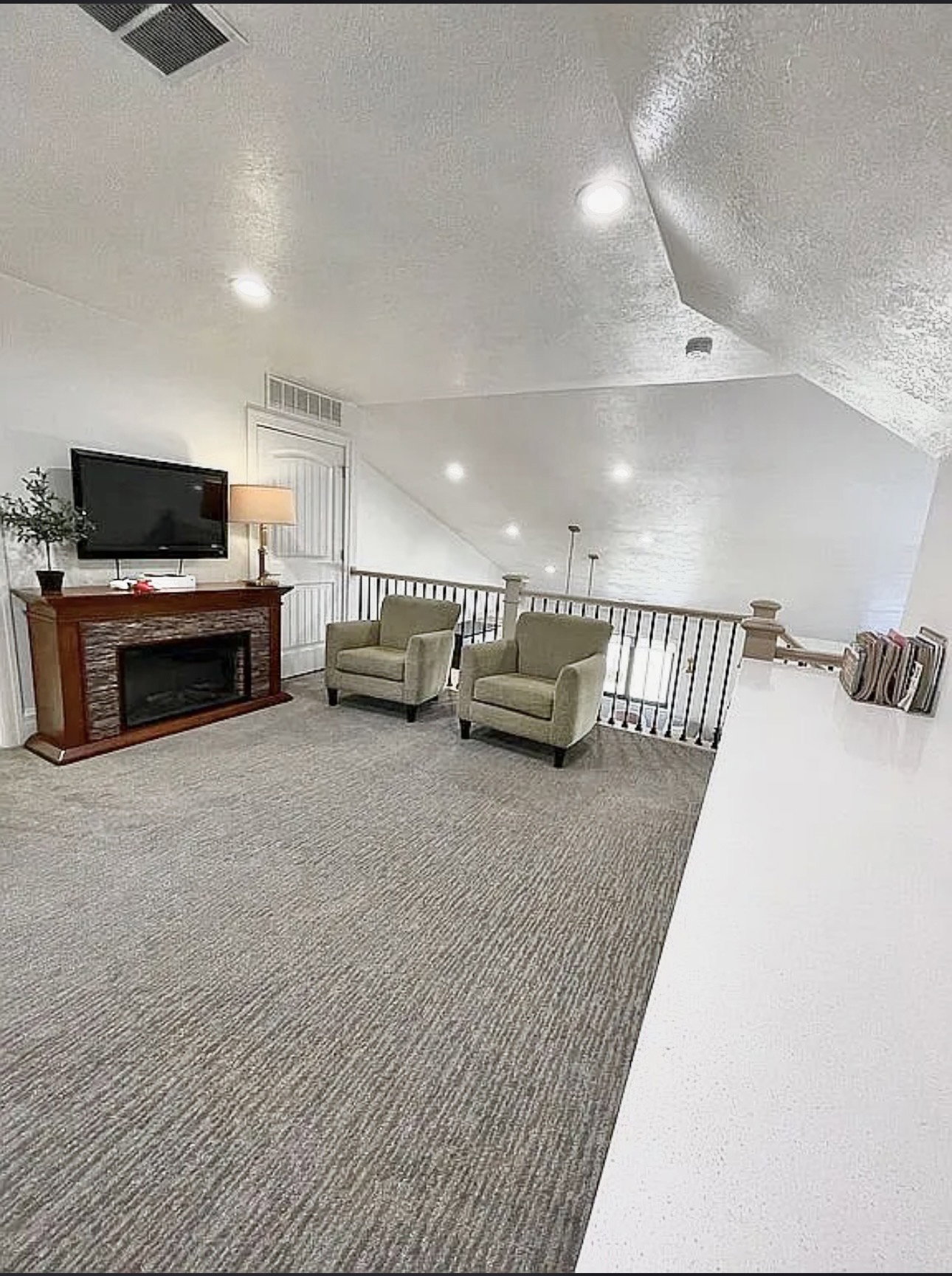 Upper-level bonus room featuring recessed lighting, textured carpeting, and a built-in electric fireplace with a stone-tile surround