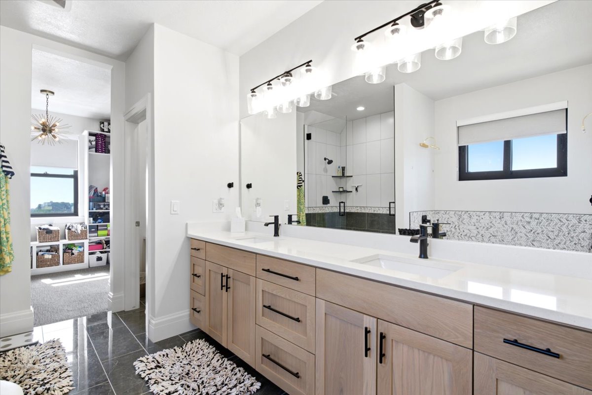 Dual sink vanity with quartz countertops, wood-finish cabinetry, and matte black fixtures
