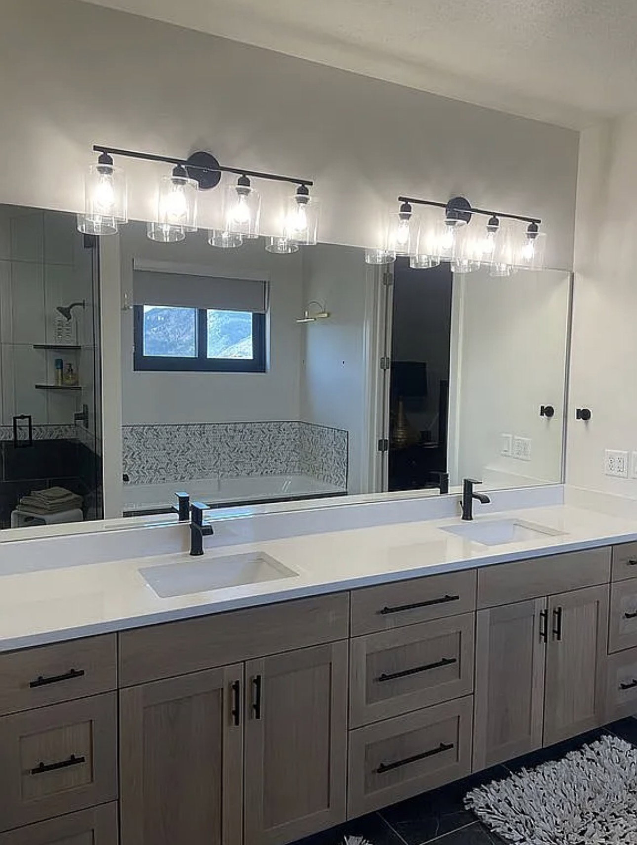 Dual vanity featuring a light wood-finish cabinetry, white countertops, and integrated rectangular sinks with matte black fixtures