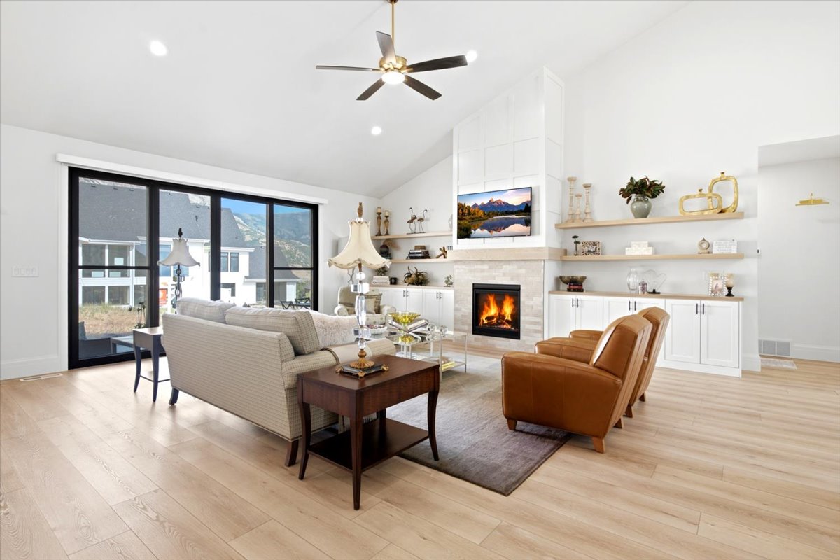 Spacious living area featuring a vaulted ceiling, wood-finish flooring, and a ceiling fan with integrated lighting