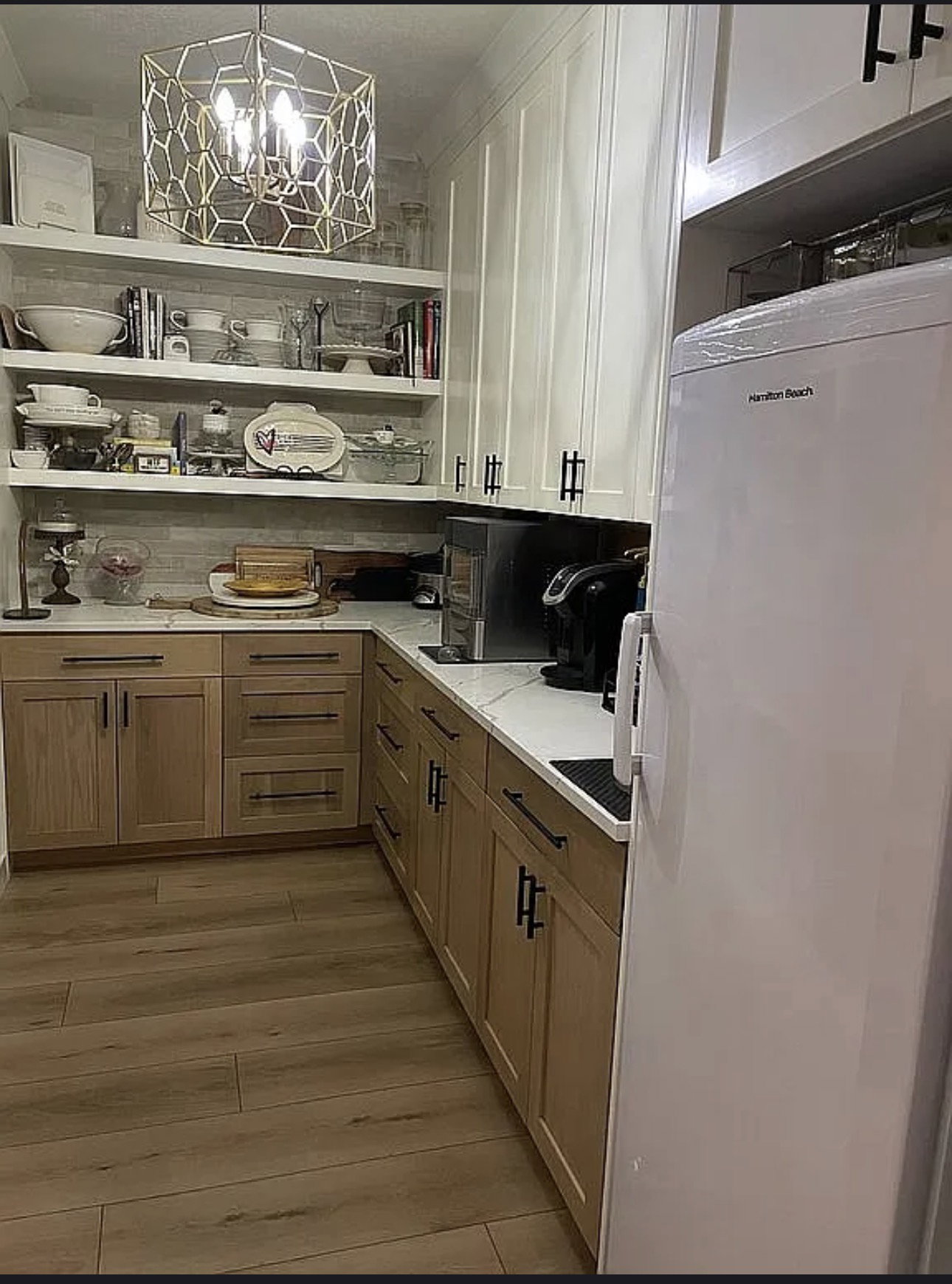 Kitchen showcasing wood-finish flooring, two-tone cabinetry with matte black hardware, white countertops, and open shelving