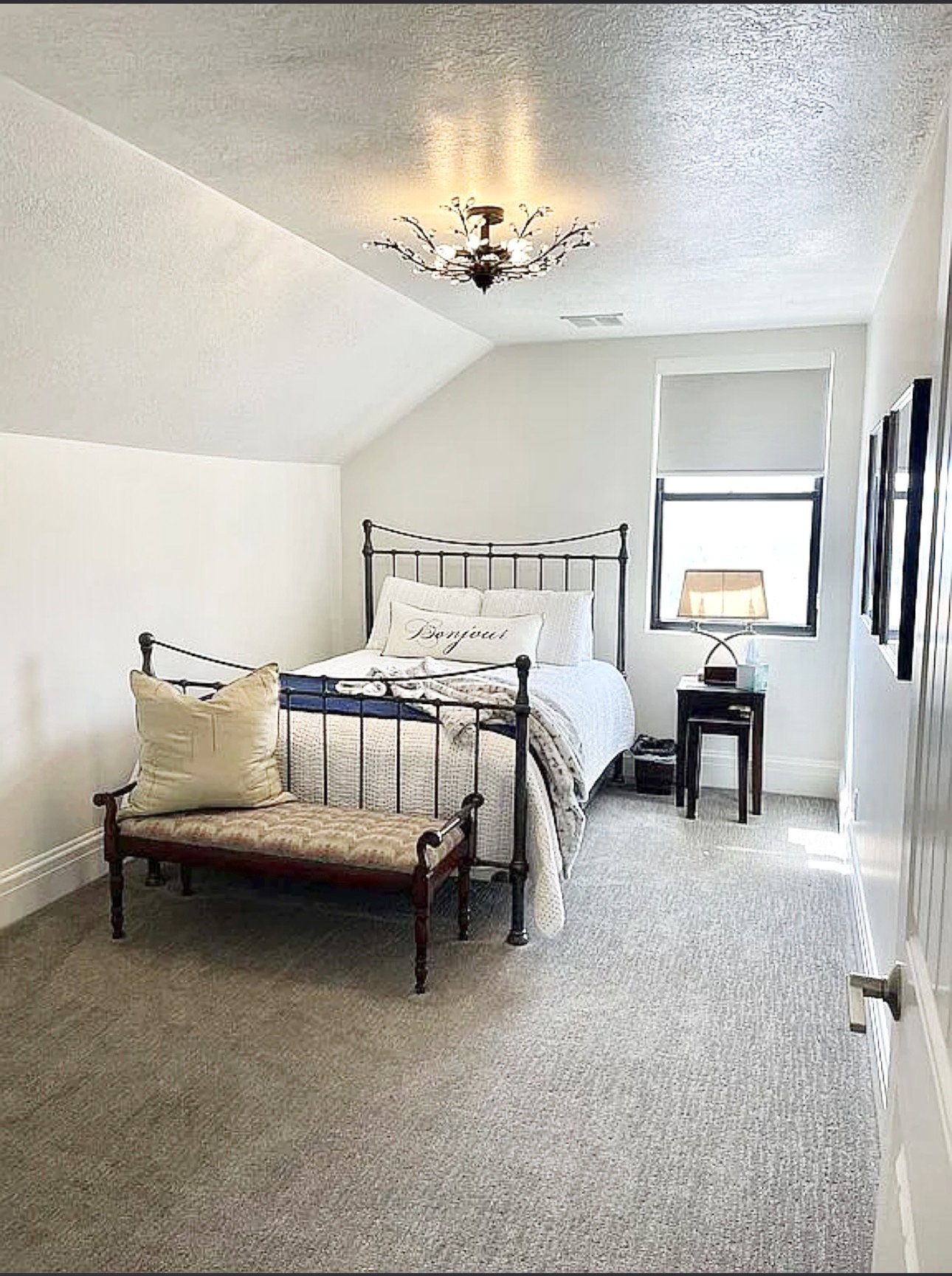 Neutral-toned carpeting extends throughout this room, featuring a sloped ceiling and a modern semi-flushmount light fixture