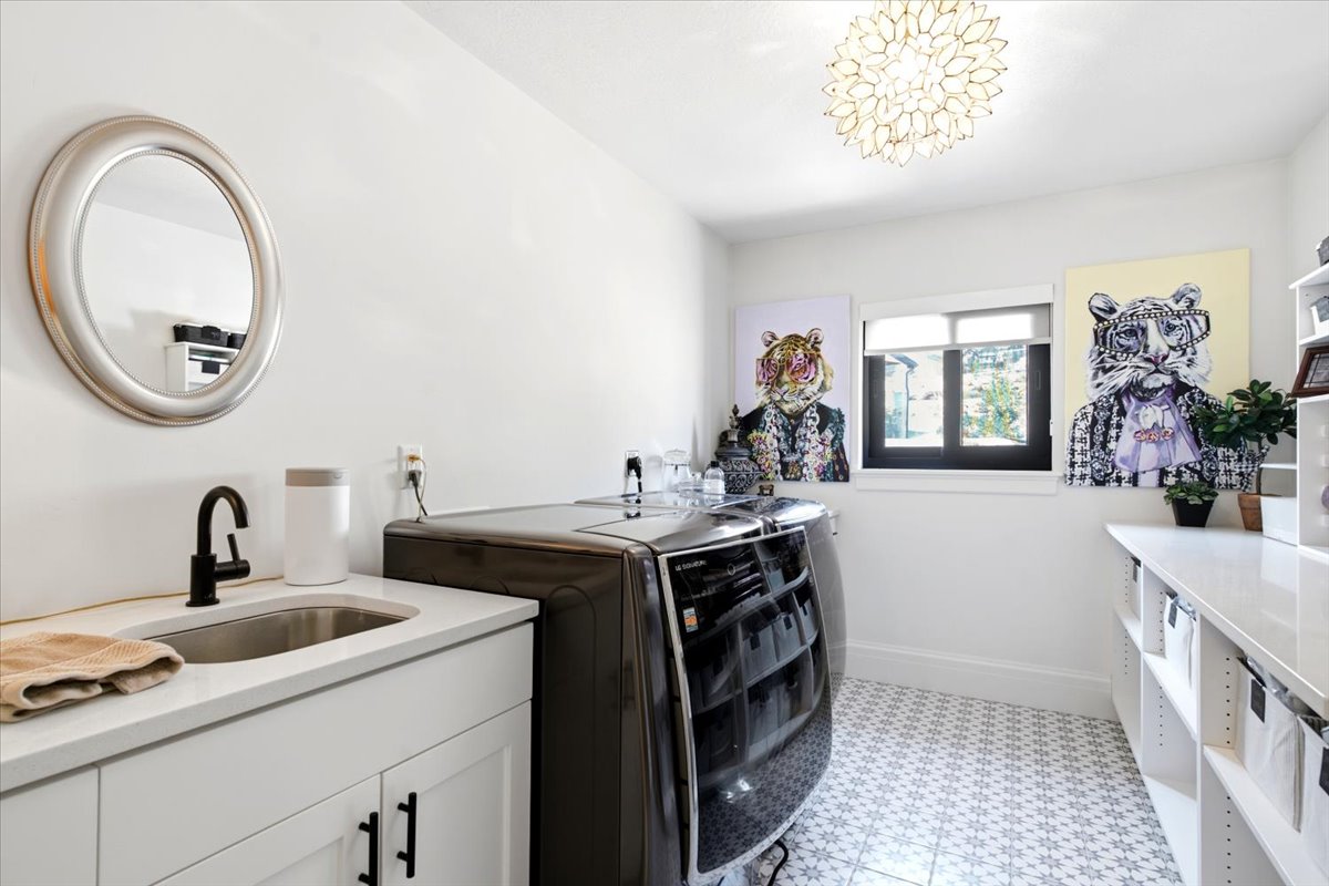 Dedicated laundry room featuring patterned floor tiles, a window, and a decorative ceiling light fixture