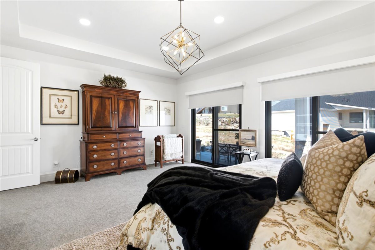 Bedroom featuring a tray ceiling, recessed lighting, and a contemporary geometric chandelier