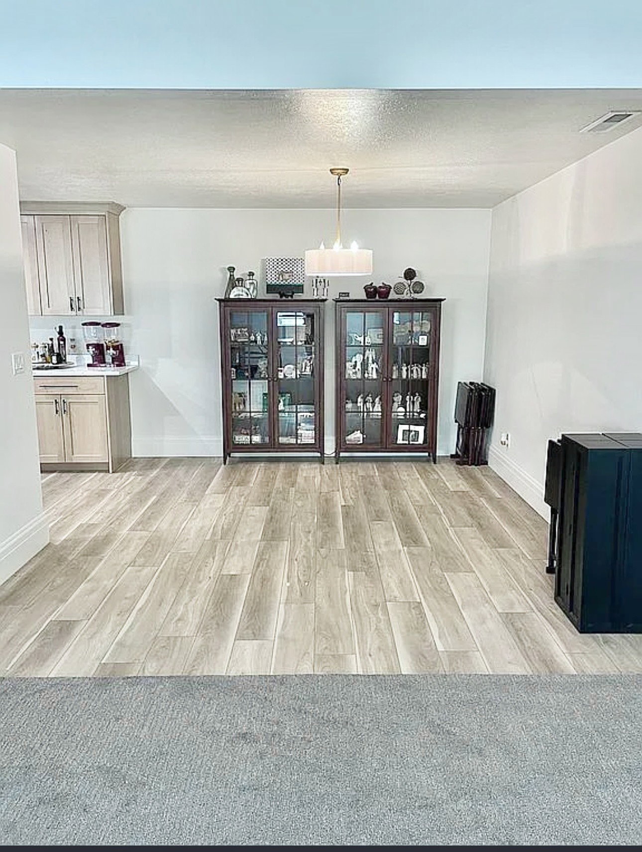 Open concept living space featuring wood-finish flooring, white baseboards, and a modern drum pendant light fixture
