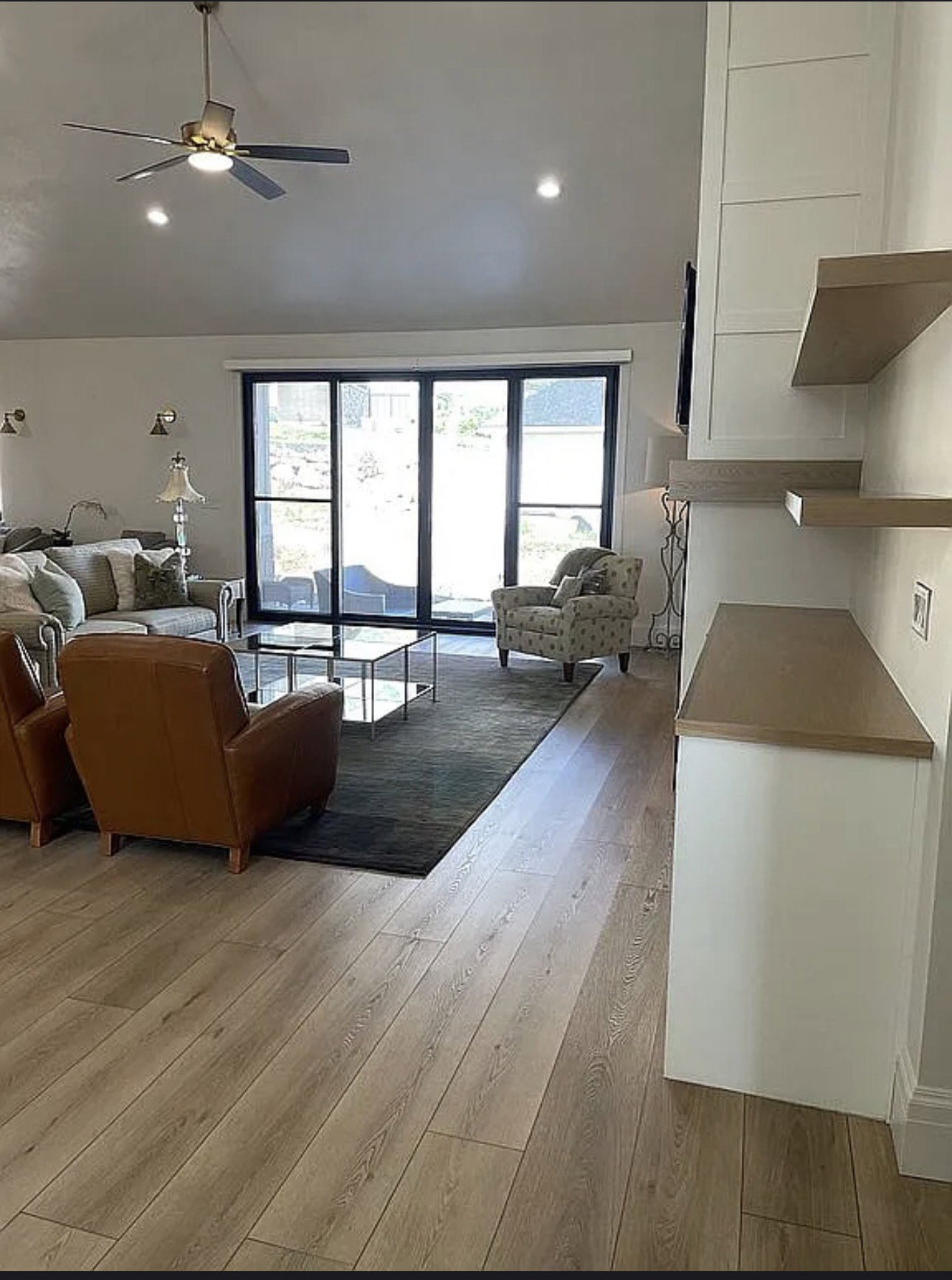 Spacious living area featuring light wood-finish flooring, recessed lighting, and a modern ceiling fan