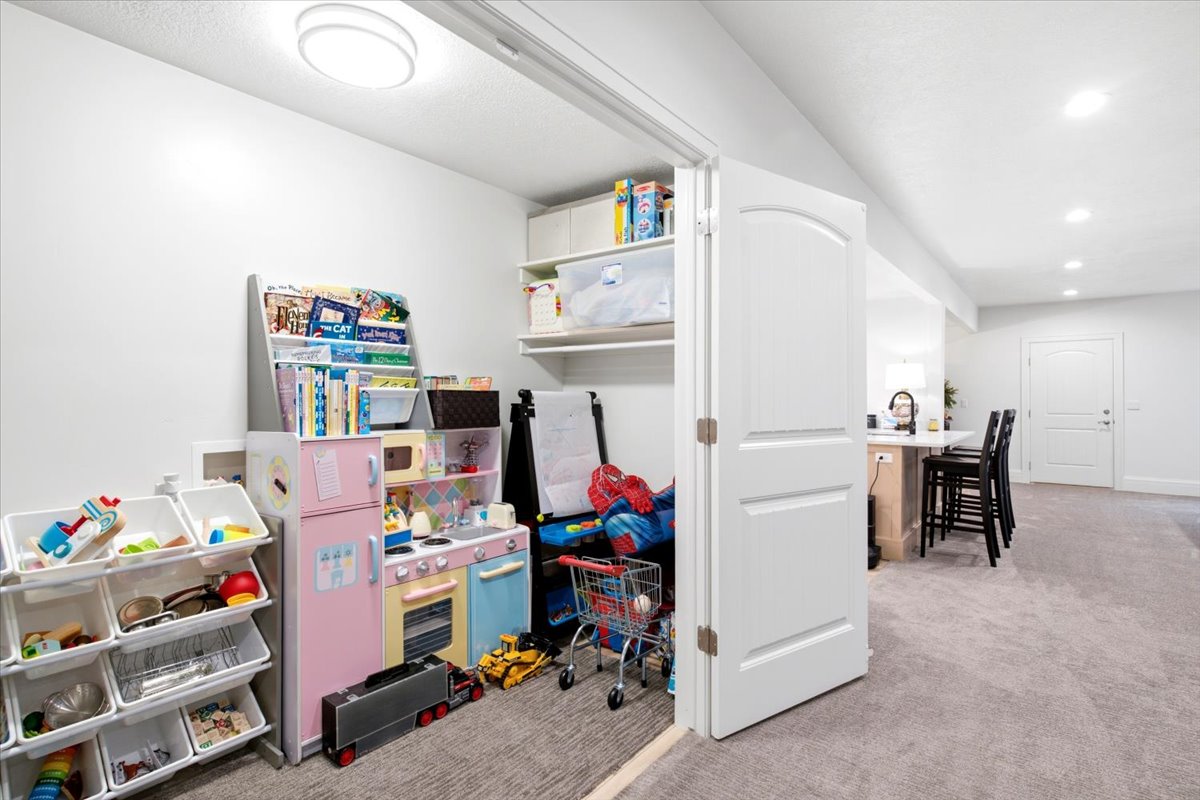 Recessed lighting illuminates the carpeted floor area, featuring a built-in closet with shelves