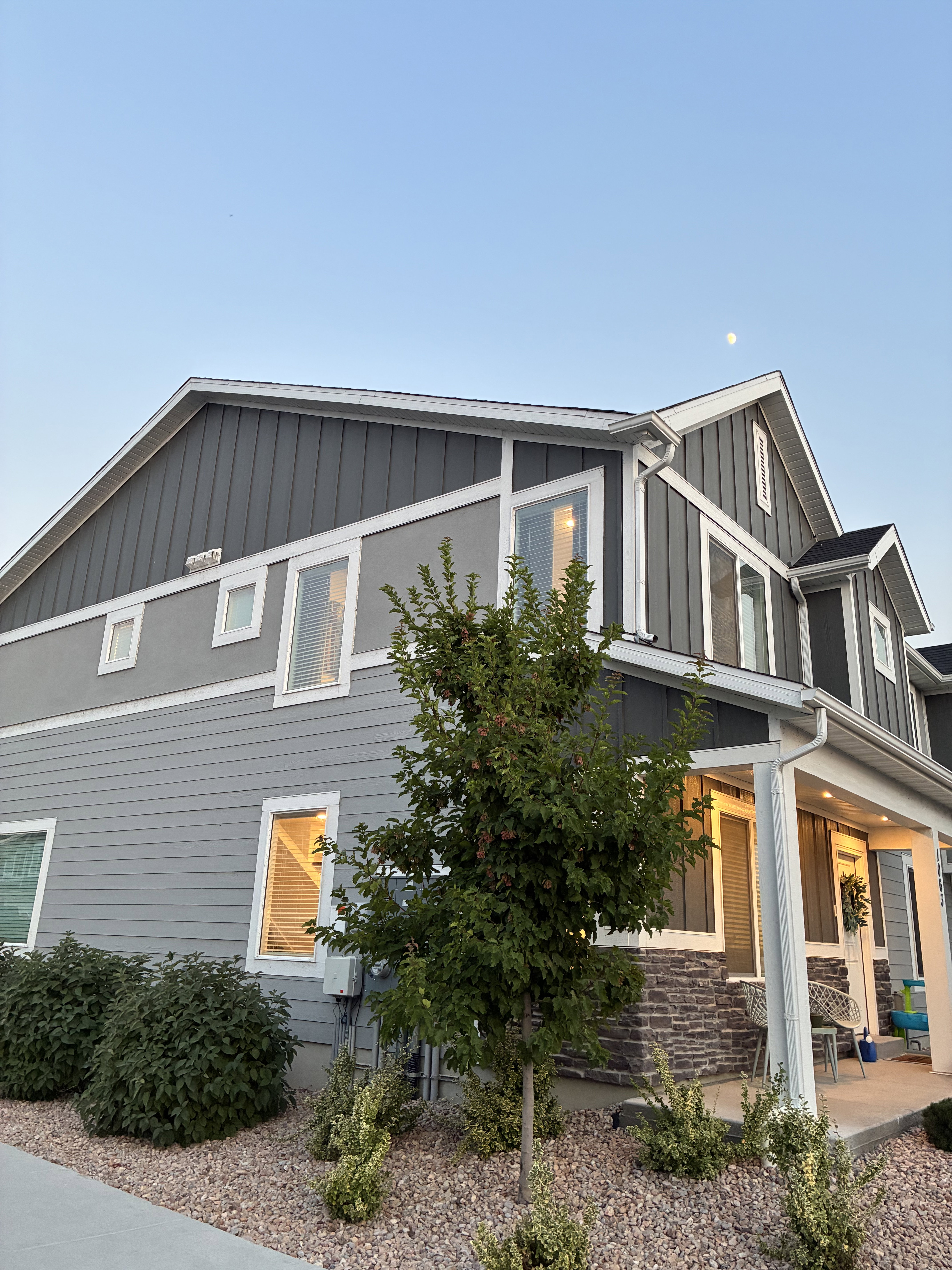 Contemporary multi-story facade featuring mixed siding, stone veneer accents, white trim, and multiple windows