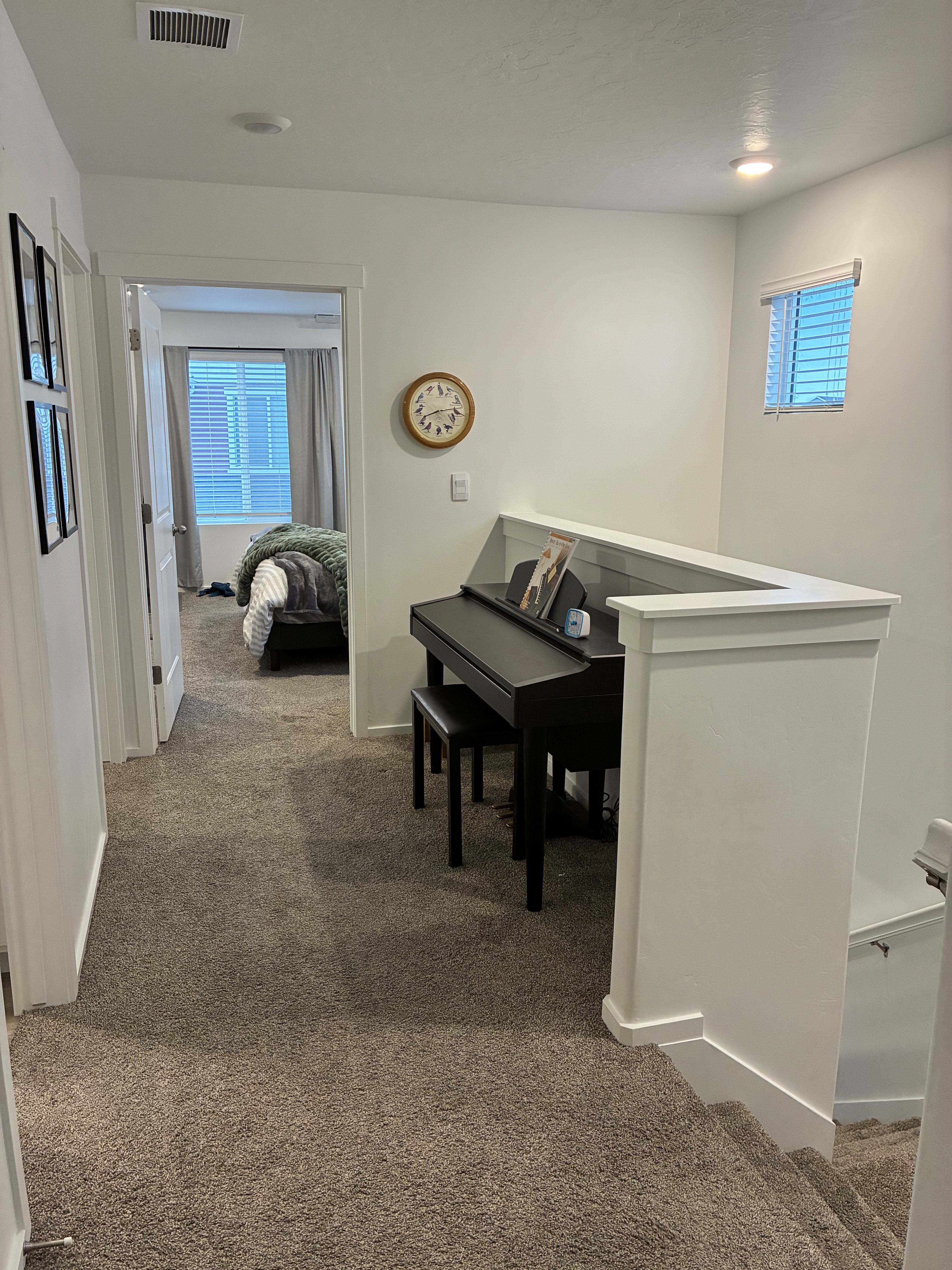 Carpeted hallway with white walls and trim, recessed lighting, and a window with blinds