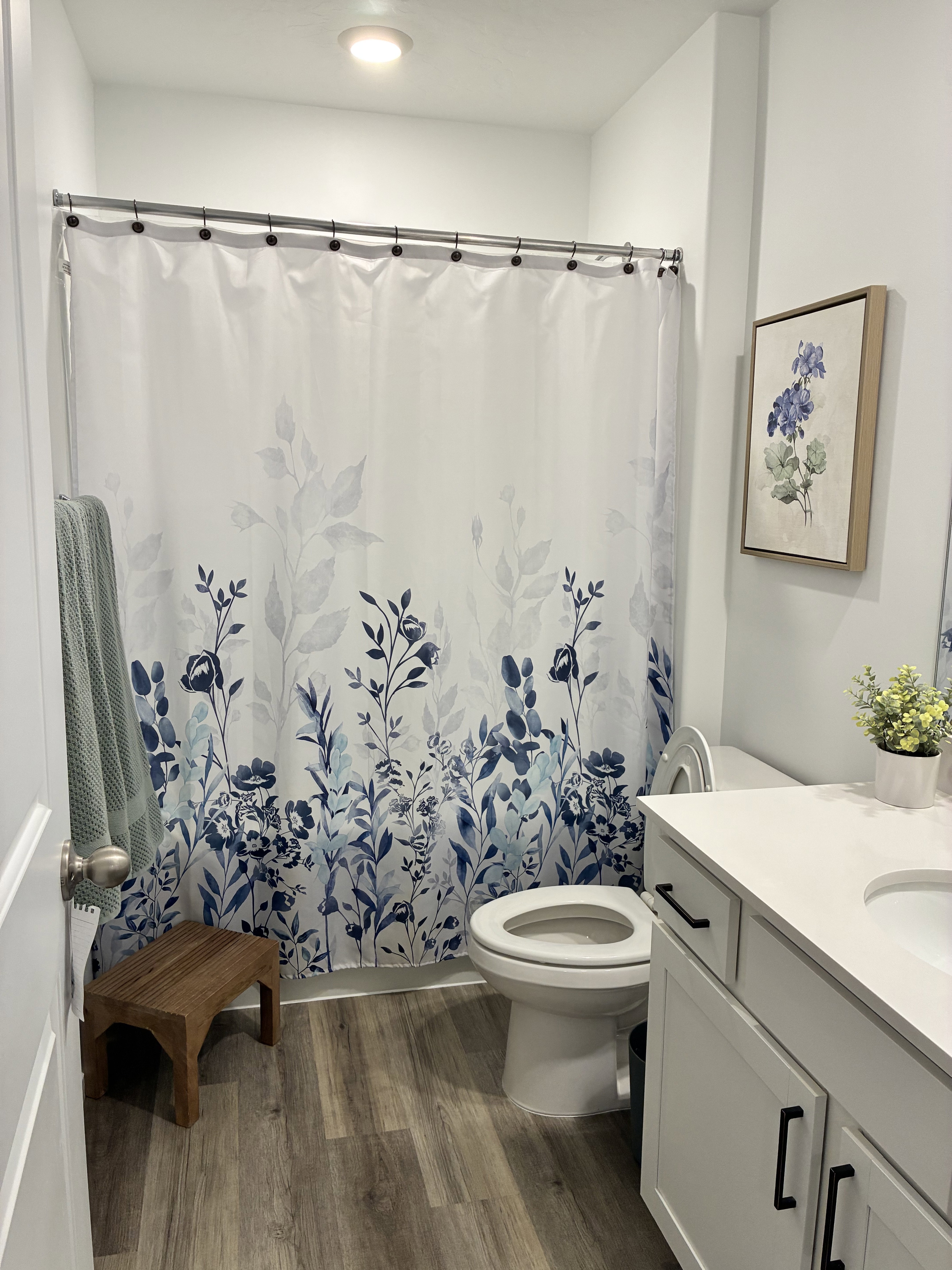 Bathroom featuring wood-finish flooring, a white vanity with a light-toned countertop, a toilet, and a recessed ceiling light