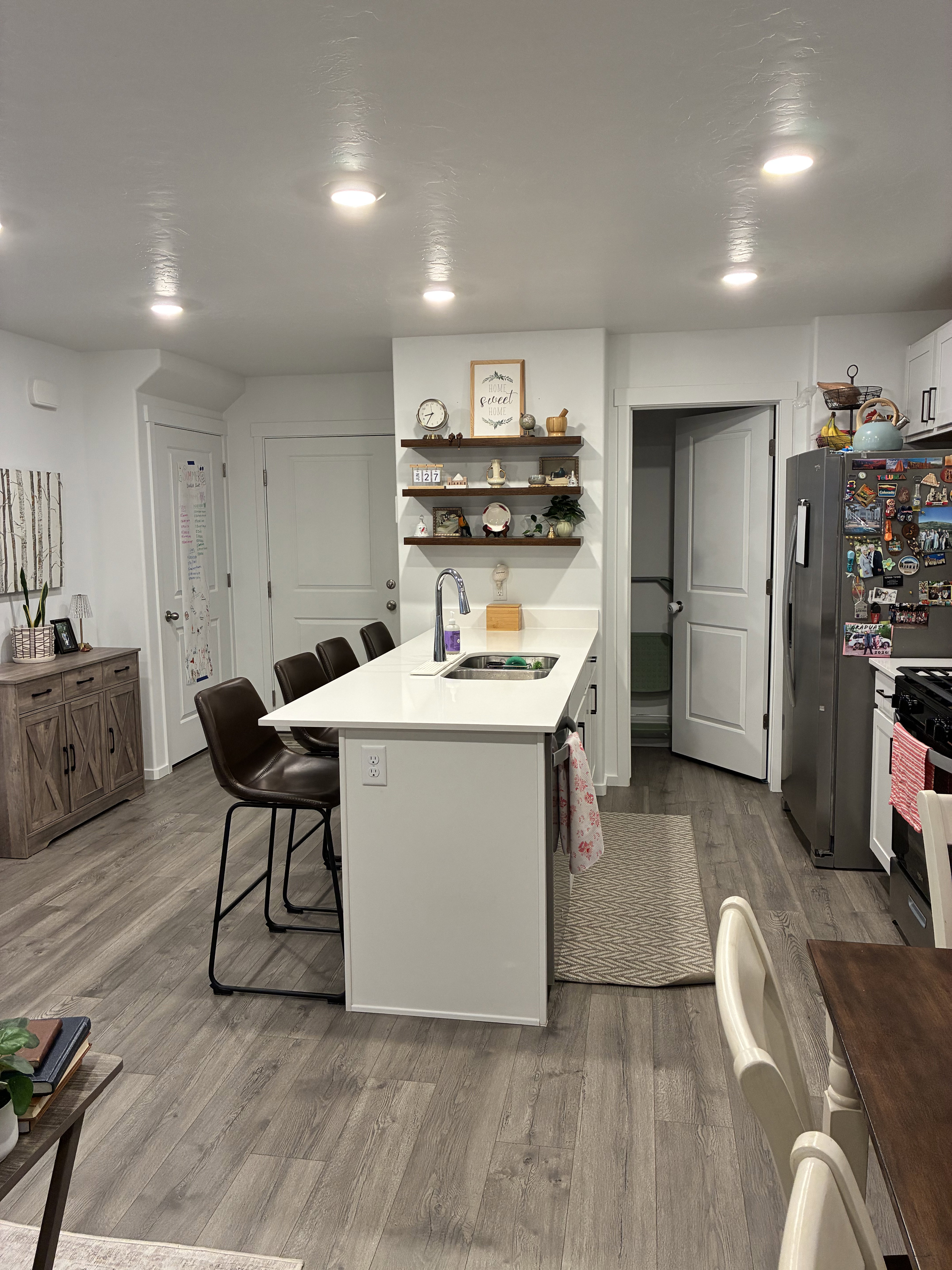 Kitchen island featuring a stainless steel sink, white countertop, and integrated seating