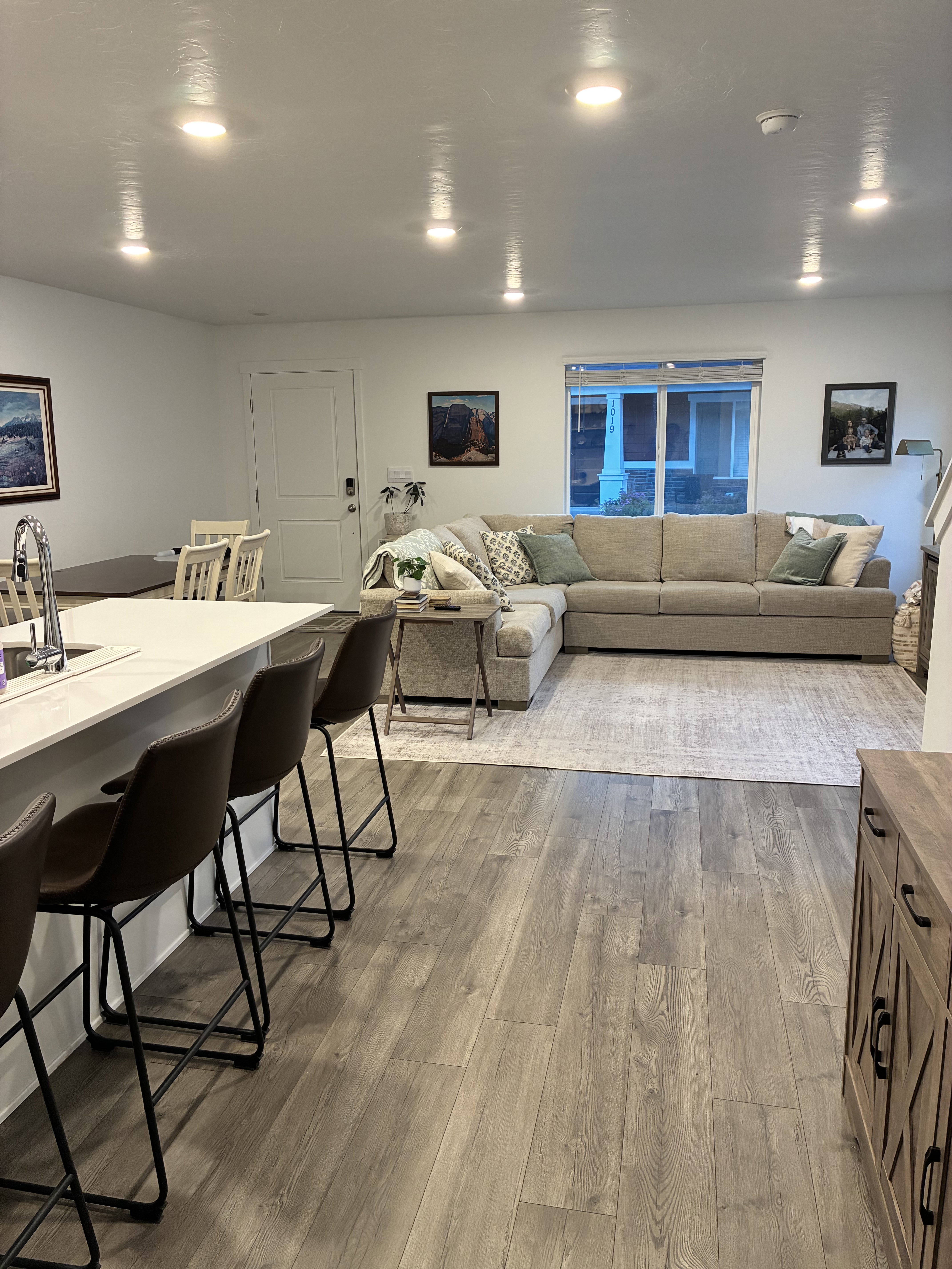 Open-concept living area with plank wood-finish flooring, recessed ceiling lighting, and a kitchen island with a light-toned countertop
