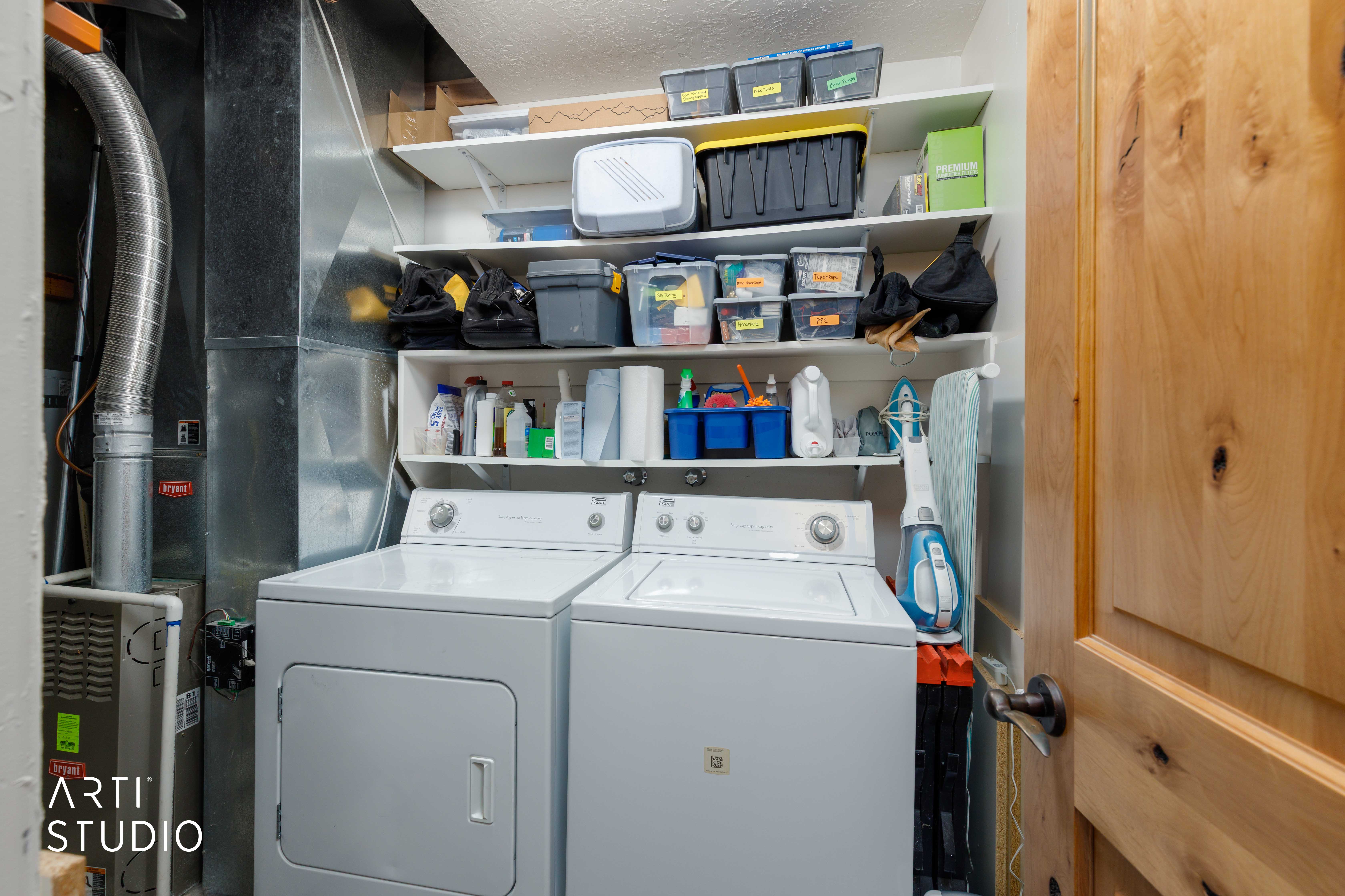 Utility area featuring a washer, dryer, built-in shelving, and a natural wood-finish door with dark hardware
