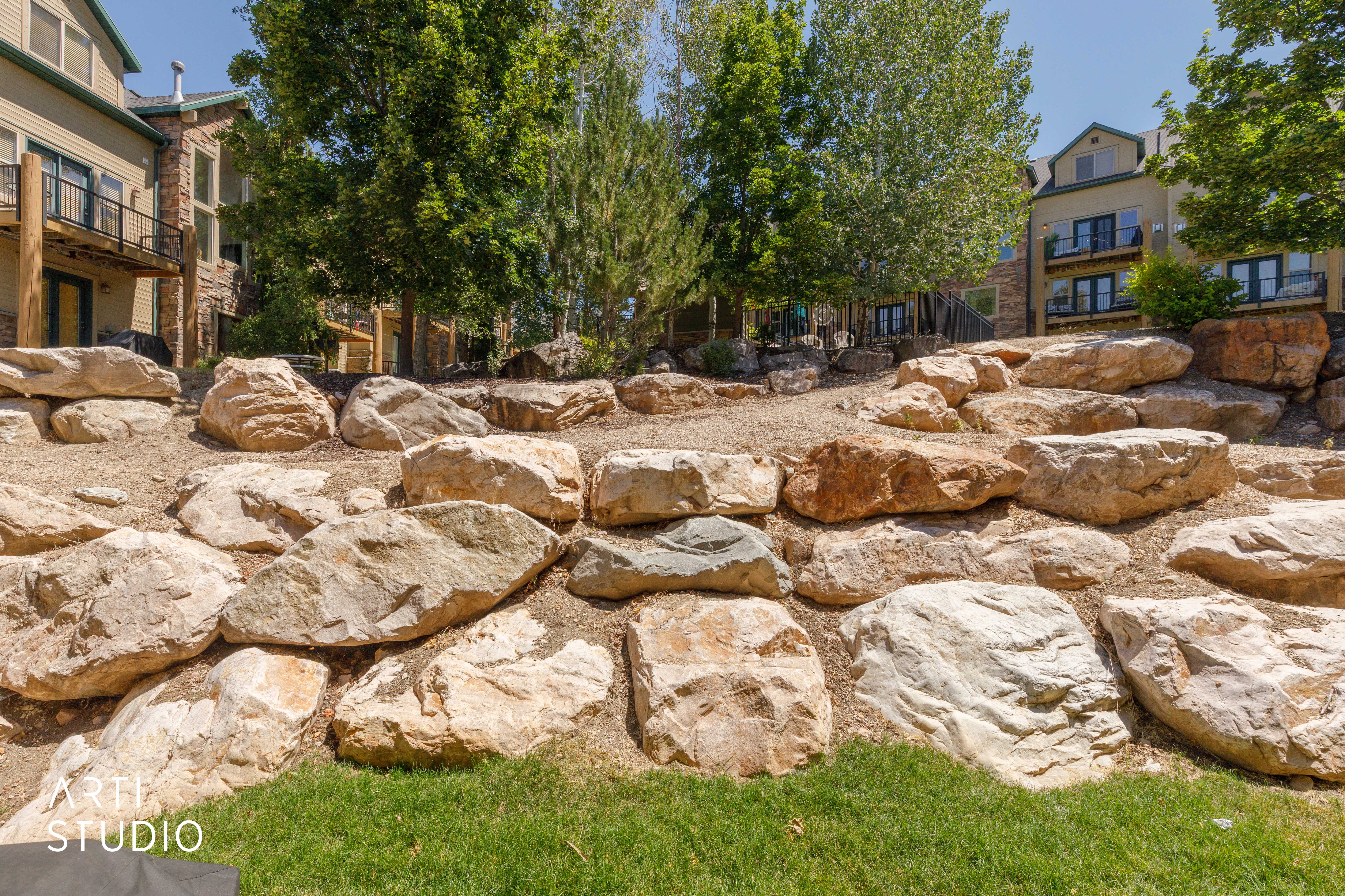 Rock retaining wall featuring large, natural stone boulders and pathway to jacuzzi