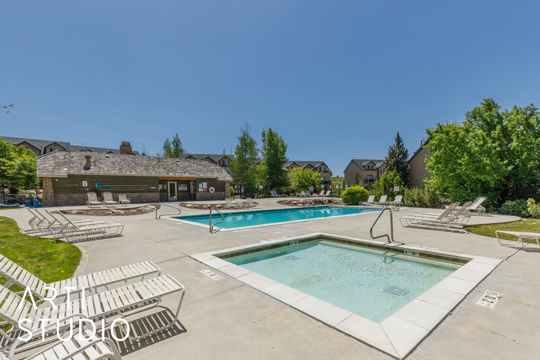 Community swimming pool and hot tub with surrounding concrete patio and abundant lounge seating