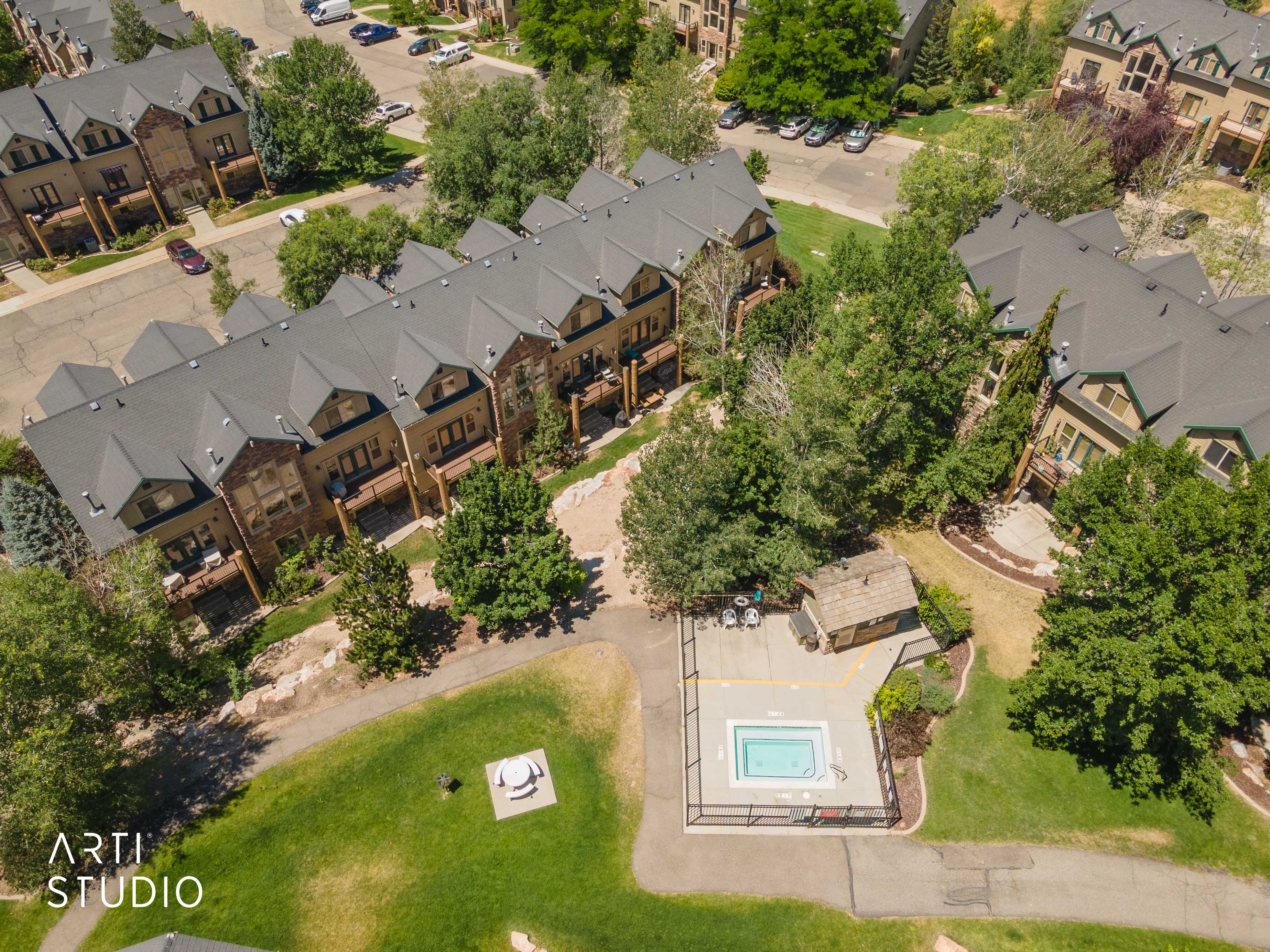 Behind Bldg 11 is a community hot tub with surrounding lounge area, nestled within mature trees and manicured green spaces